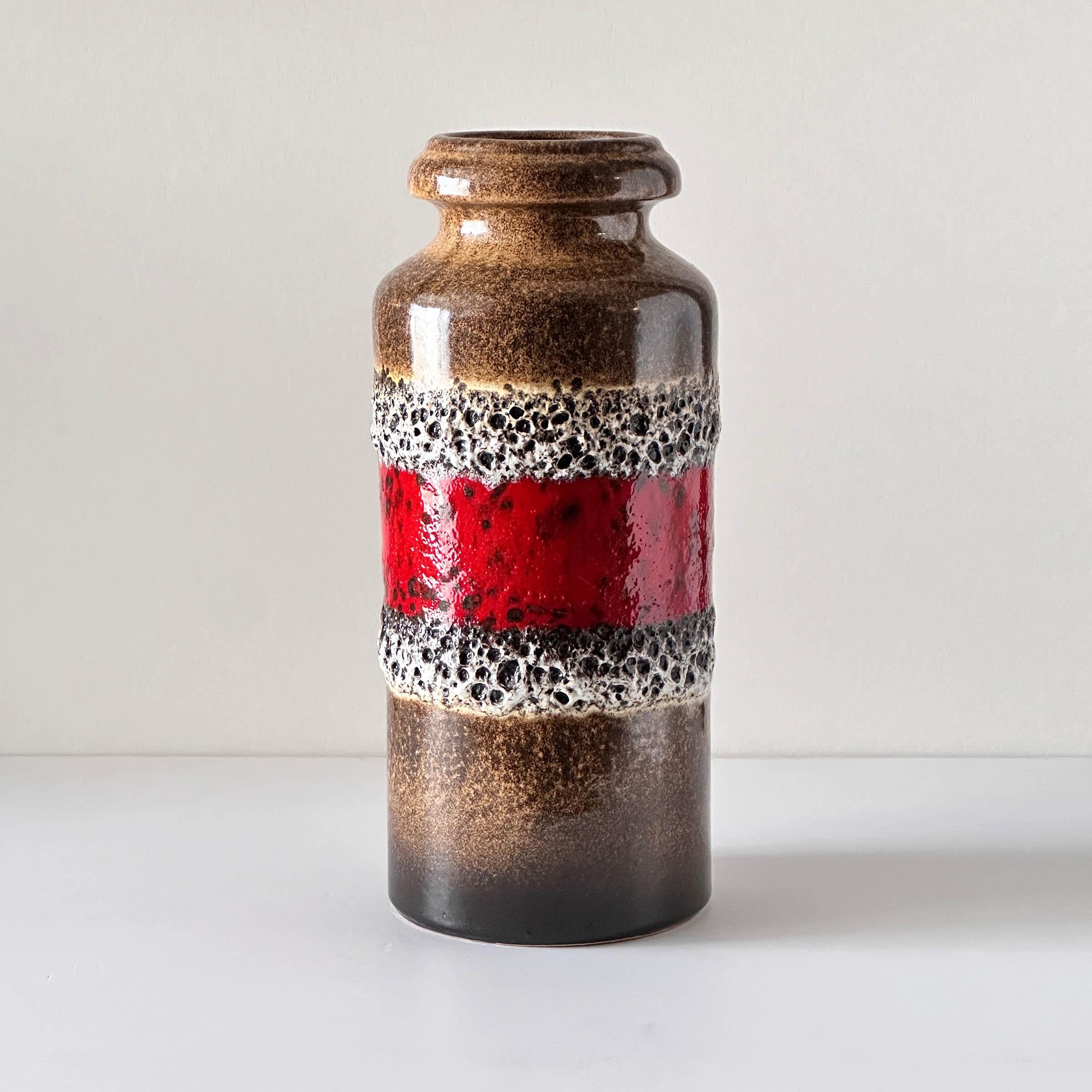 This vintage Scheurich shelf vase features alternating gloss and matte fat lava banding in black, white, and red, across a textured tobacco color glazed background. The water-tight glazed interior is black. Made in West Germany, circa 1960 – 1969.