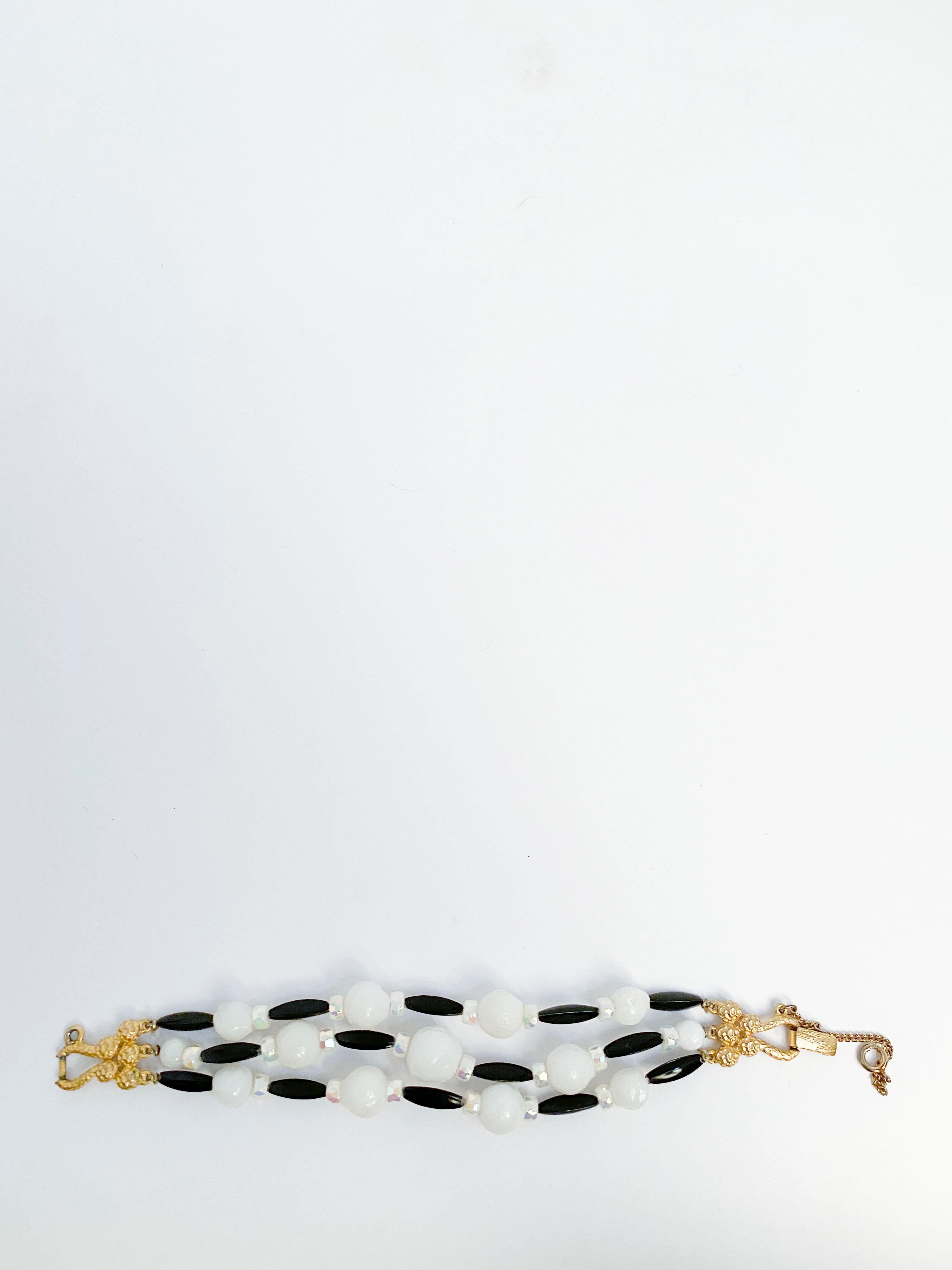 1960s Schiaparelli Lucite beaded bracelet with tress strands of black white and opaque pearlesent beads. Finished with a gold tone clasp and safety chain