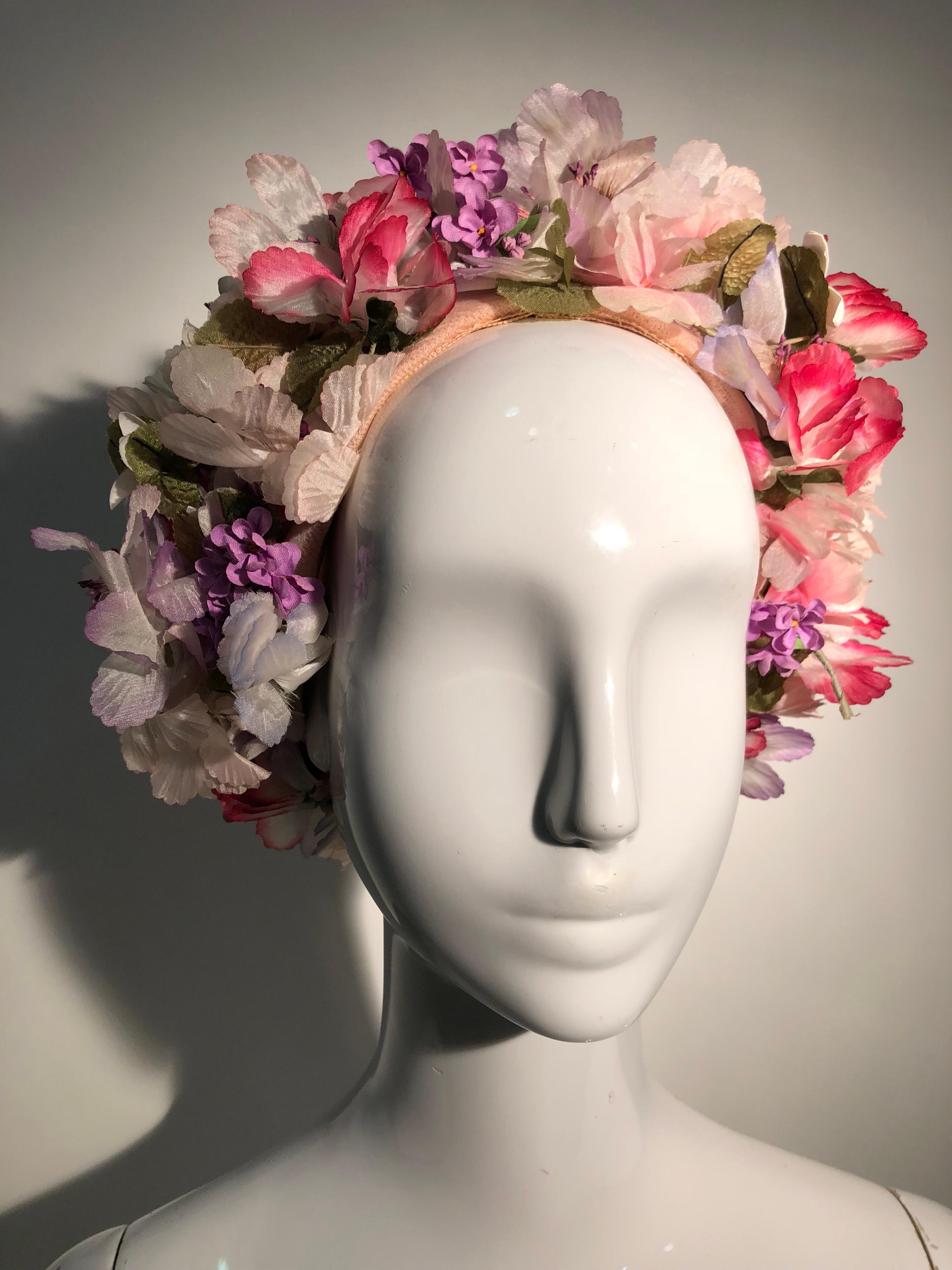A beautiful never-worn 1960s Elsa Schiaparelli spring hat of wrapped straw and silken floss, in shades of pale pink,  with a heavy band of beautiful silk flowers at the edge. Still has original Shocking Pink Schiaparelli hang tag!