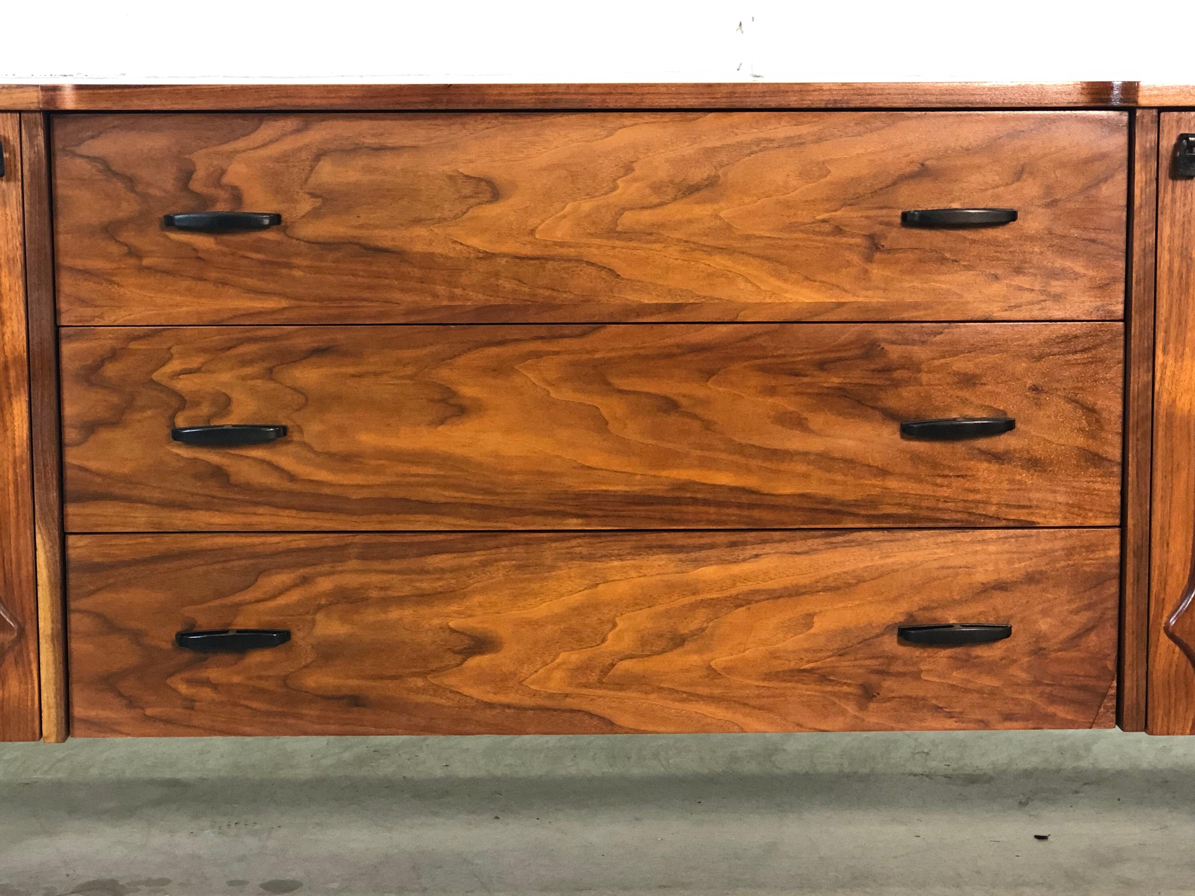 Vintage 1960s sculpted walnut low dresser with nine drawers. The dresser doors have a beautiful walnut sculpted design. The side drawers measure 17” W x 5.25” H. The middle drawers measure 37” W x 5” H. The dresser has been completely refinished