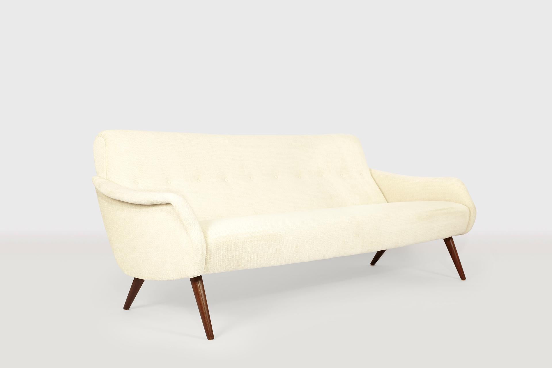 This rare and highly elegant sofa features stunning comfort and impeccable style. This unique piece has wooden legs and unique sculptured armrests. The shaping of the piece could be the Scandinavian pendant to the Italian MarCo Zanusos armchairs.
