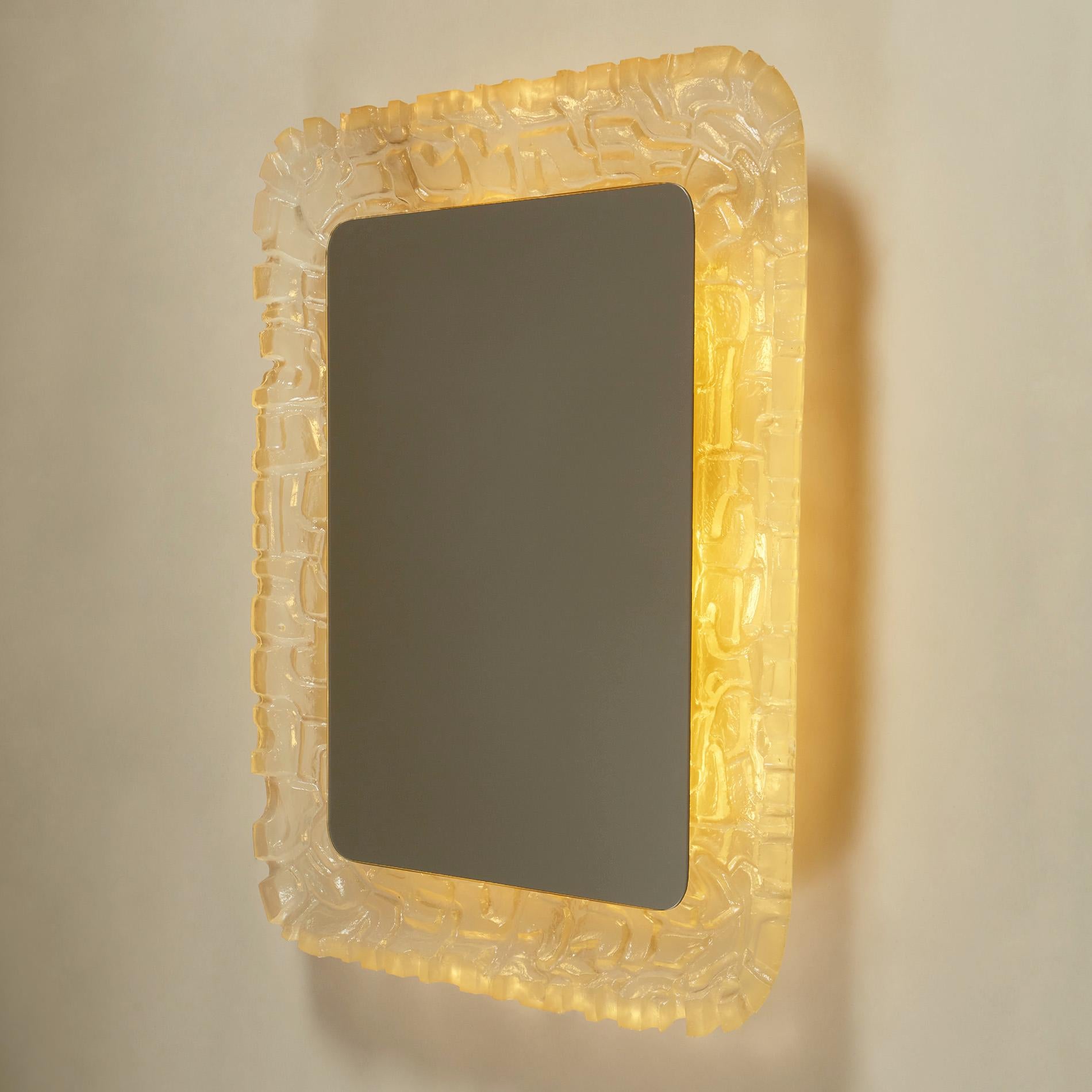 Miroir rectangulaire inhabituel avec éclairage arrière. Le cadre concave est sculpté dans des cubes irréguliers de résine froide et brillante.