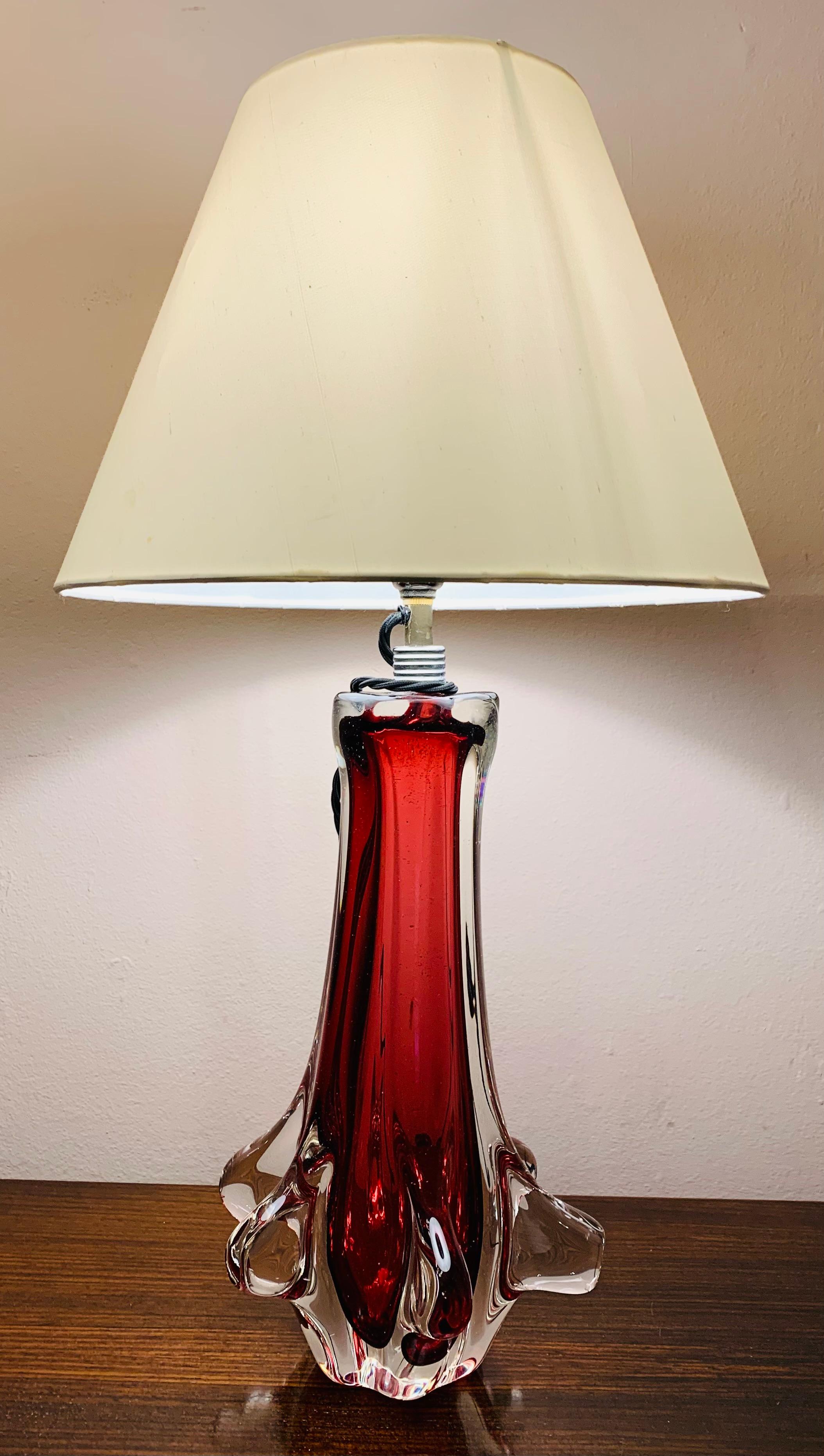 1960s Italian Murano handblown glass table lamp with a ruby red interior encased in clear glass. The lamp base is surrounded around the lower section by clear glass feature smooth fins. In the style of Vetreria Archimede Seguso. 

Rewired with a