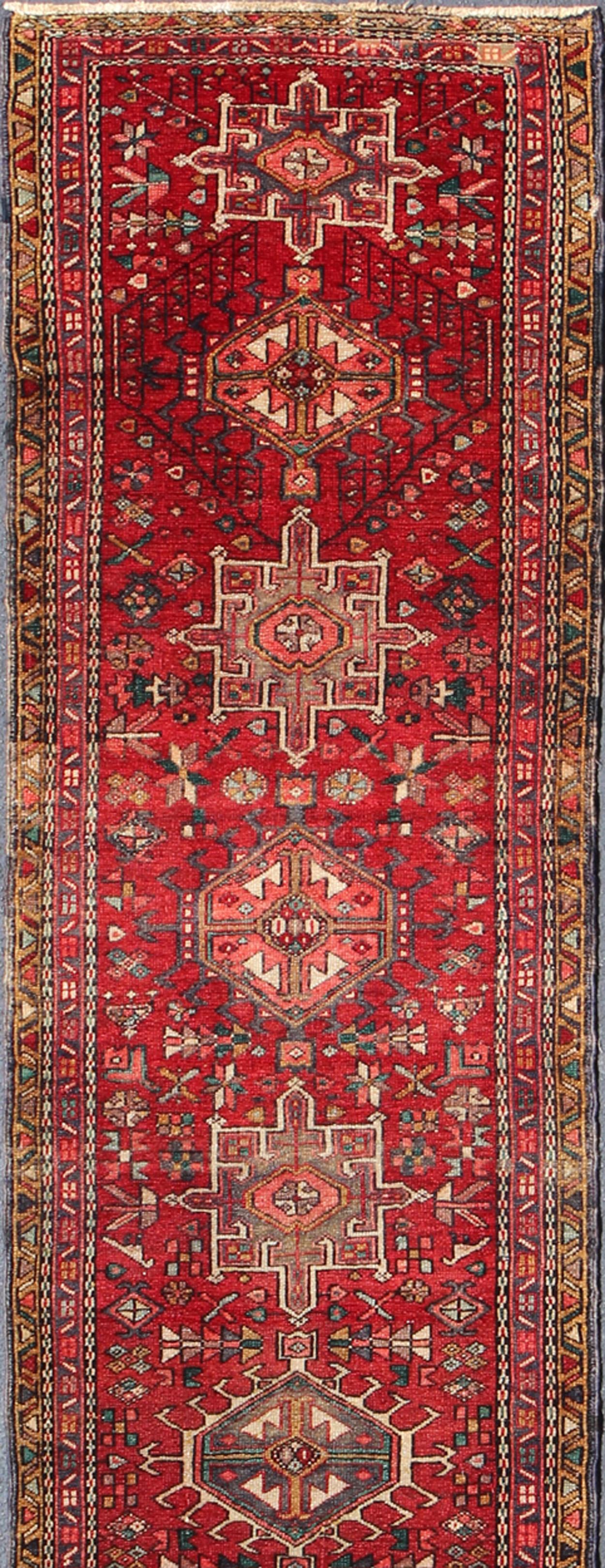 This mid-20th century, handwoven Semi Antique Karadjeh runner features a red-colored field imbued with ornate medallions. A beautifully drawn multi-tiered border surrounds the entirety of the piece.  The articulation of the motifs is excellent and
