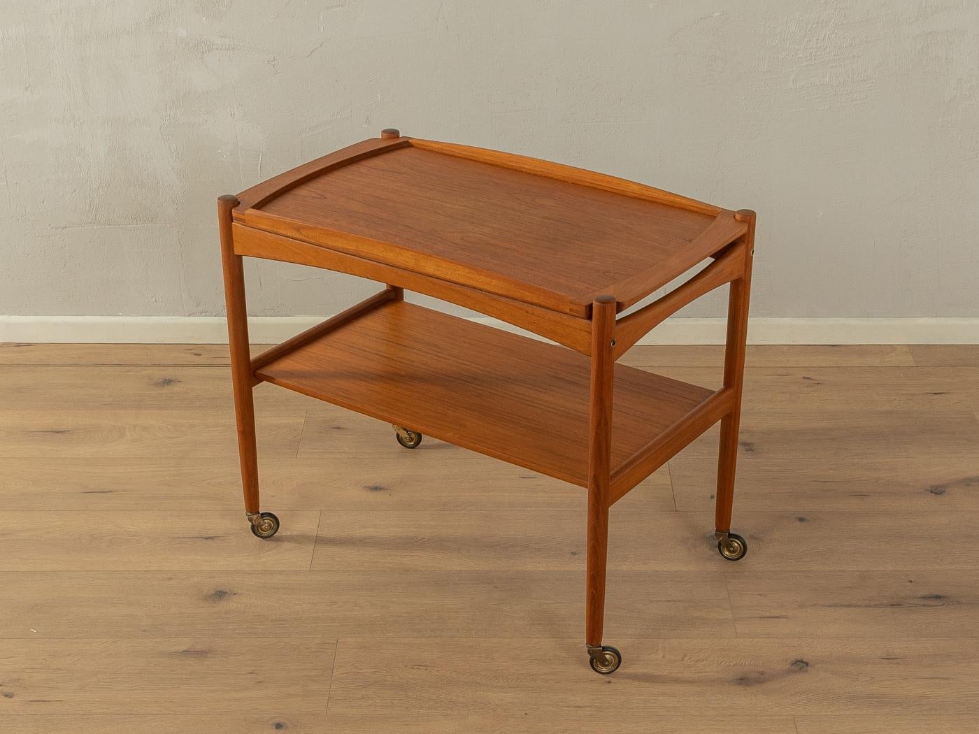 Classic serving trolley from the 1960s. Solid teak frame with two shelves in teak veneer and plastic castors. The upper shelf can be used as a tray.

Quality Features:

    accomplished design: perfect proportions and visible attention to detail
   