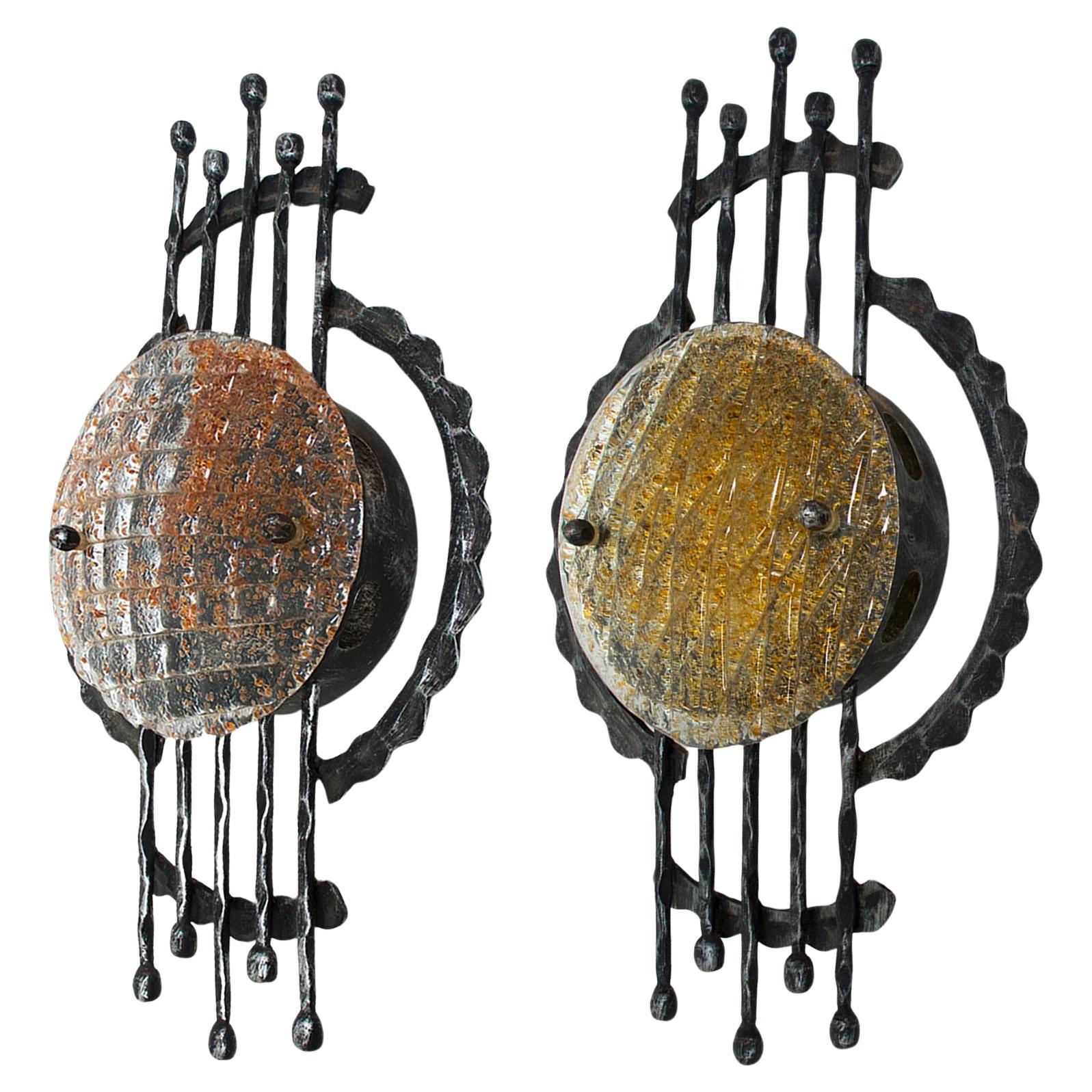 Beautiful set of two brutalist mid century wall sconces designed by Tom Ahlström & Hans Ehrich. 
Nice Brutalist shape with wrought iron and thick Murano glass (one glass with amber tones, the other one with yellow tones). 1 E27 socket per lamp. 
The