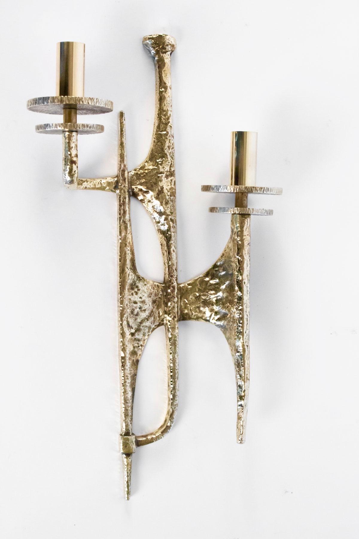 Each sconces features two lighted arms which form an asymmetrical pattern. 
Made of gilded bronze with polished brass bulbs sockets. 
Their design can be qualified as an elegant brutalism.

2 bulbs per sconces.
 