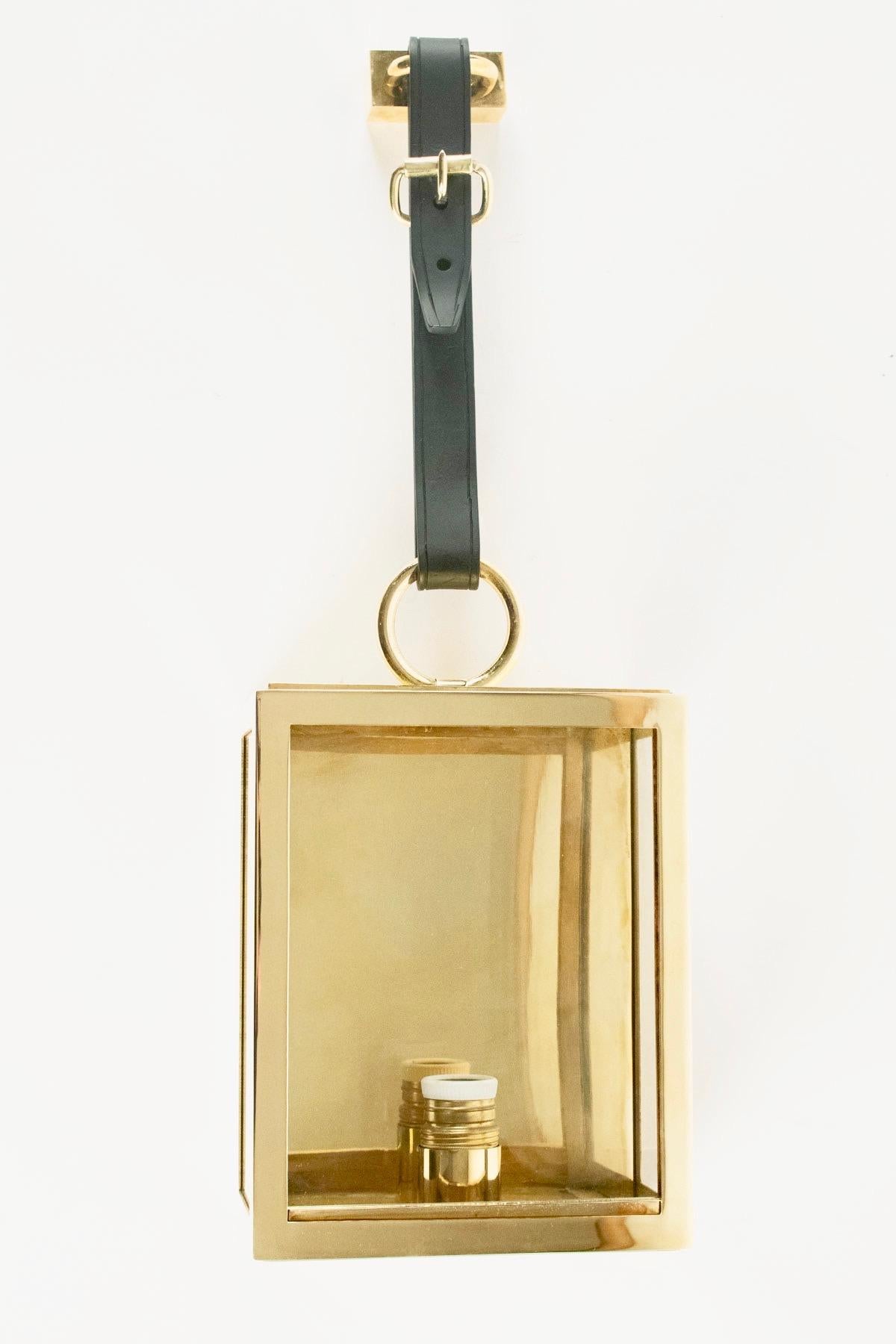 Each sconce consists of a polished gilded brass box with 3 glass windows and one ring on the top.
The lanterns are hanged with wrought iron strip that imitates a leather belt with a brass buckle.

One bulb per sconce.