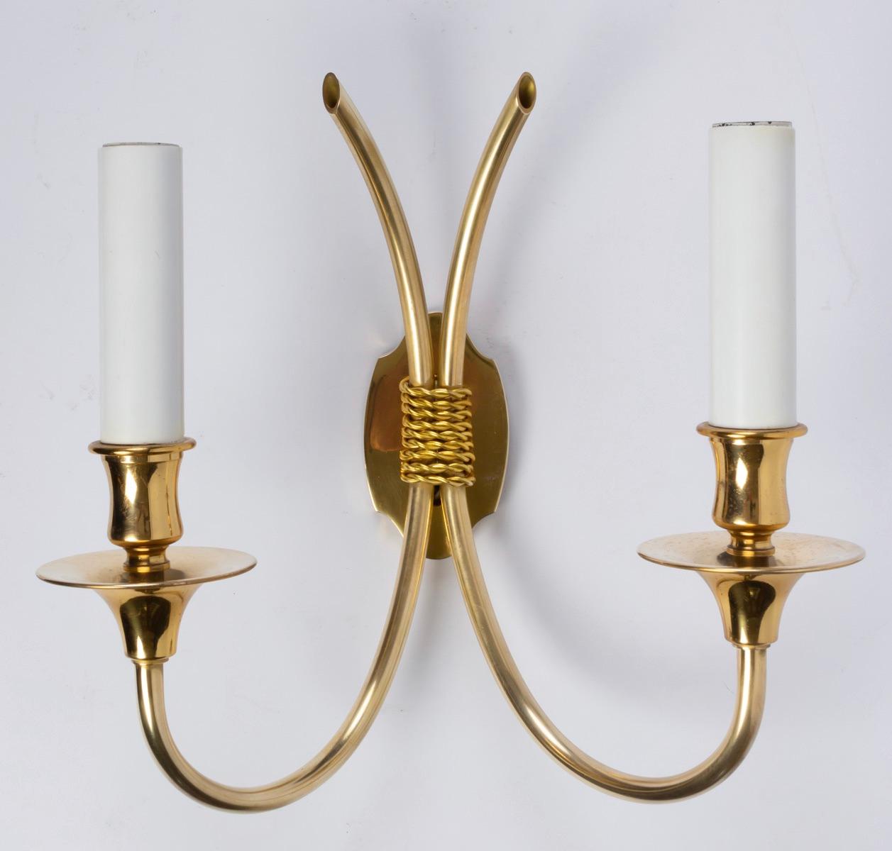 Elegant set of four Maison Honoré gilded brass sconces.
All made of gilded brass each sconce features two curved arms gathered together with brass cord.
The back plate is shield shaped. Two bulbs per sconce.
 