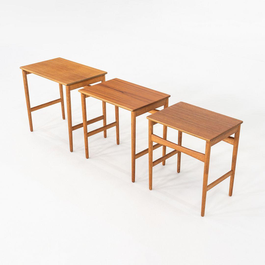 This is a Set of Three Graduated Nesting Tables dating to the 1960s, designed by Hans Wegner for Andreas Tuck in Denmark. The tops of the tables are made with rich teak, and the frames are composed of oak. The tables fit neatly underneath one