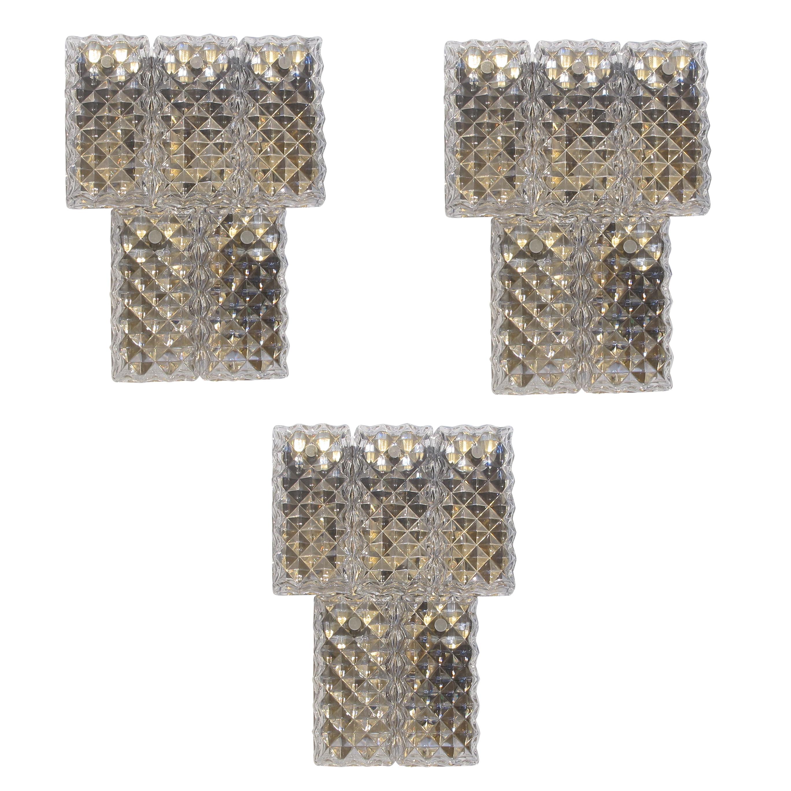 Set of three two-tier Kinkeldey wall lights from the retro period, 1960s. Crafted with meticulous attention to detail, each light features textured glass plates with prism shapes to refract the light. Each wall light holds four panes of glass held
