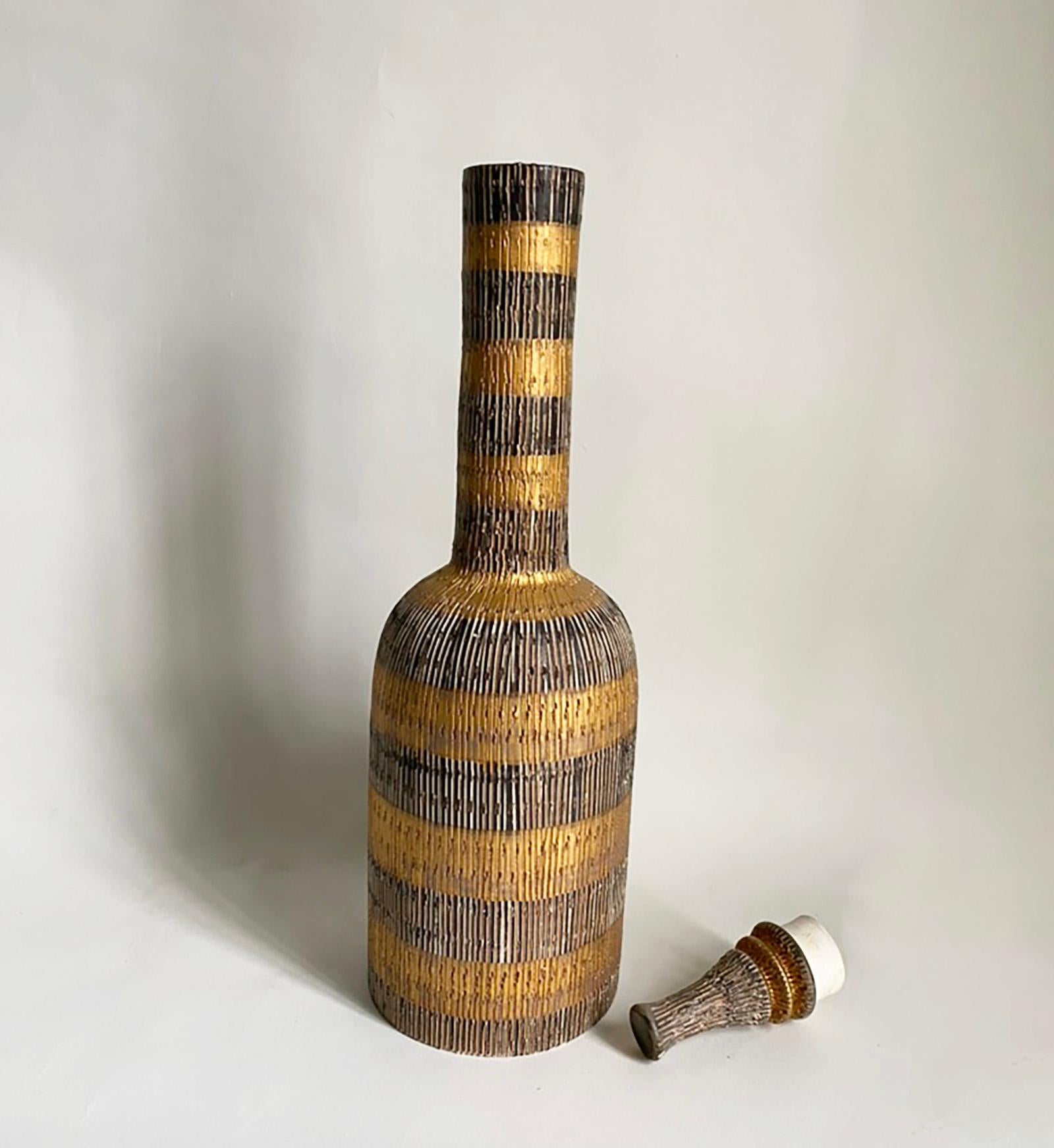 Here is a very decorative and striking stopped bottle from the Seta series designed by Aldo Londi for Bitossi of Italy. The bottle features an incised design in shades of brown and gold metallic glazes. The bottle measures 18