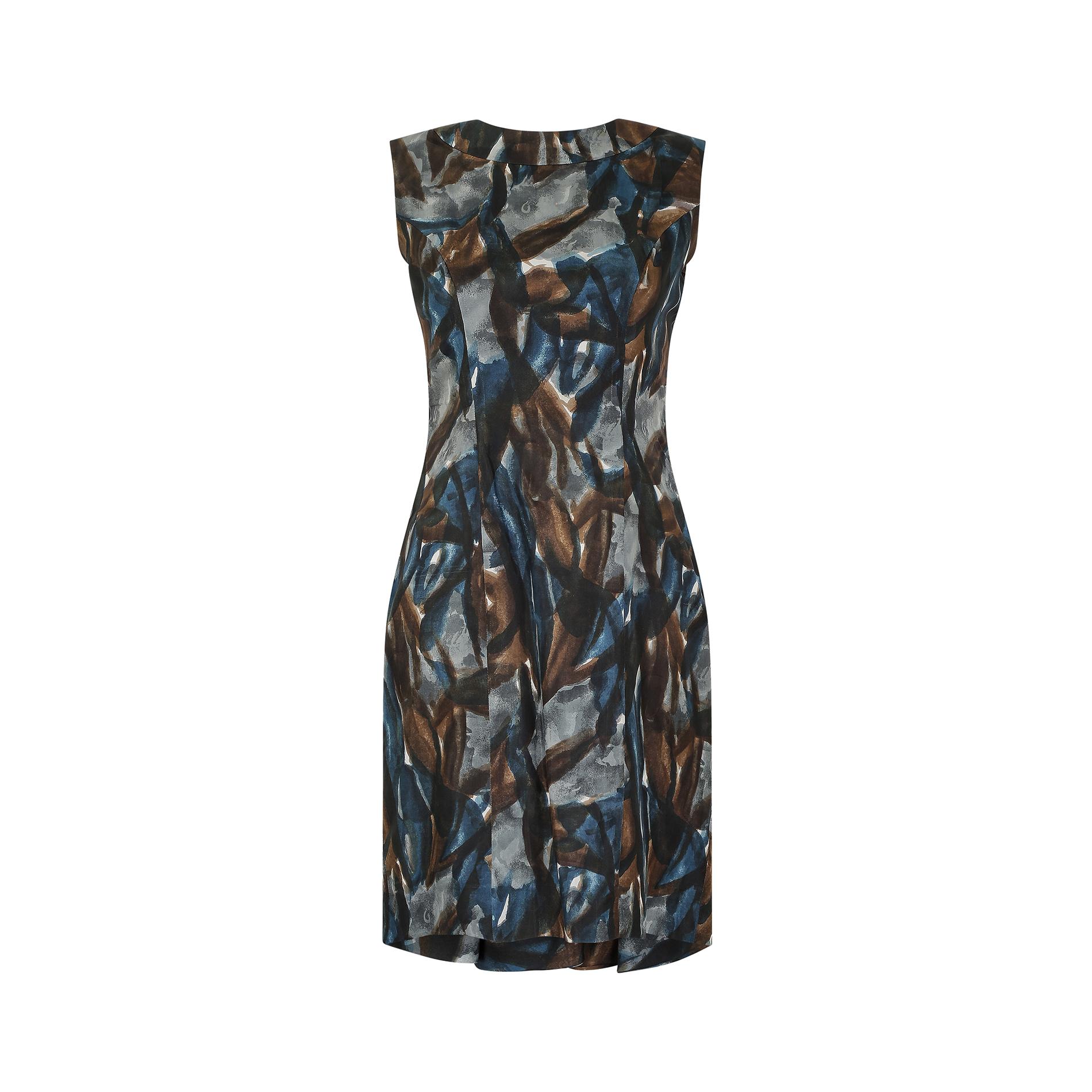 This 1960s Sharene Creations dress is cut in a figure hugging sheath design and features a mid century abstract pattern of mottled greys, blues and browns in a painterly style print. It has a high, softly rounded neckline to the front and a cutout