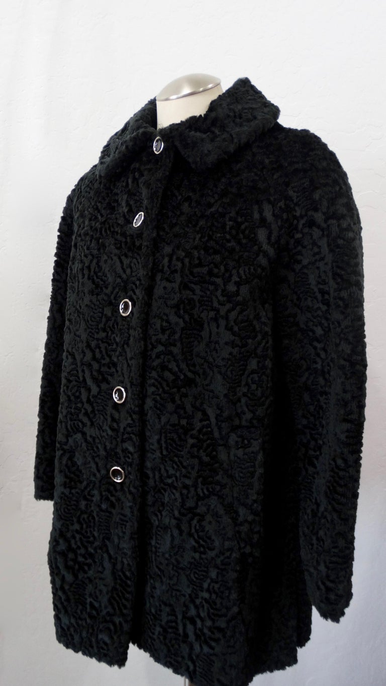 Elevate your winter looks with this gorgeous coat! Circa mid to late 1960s, this mid-length pea coat is made of black faux fur and features a sheared swirl motif. Includes shiny black buttons with a silver hardware down the front and on the cuffs.