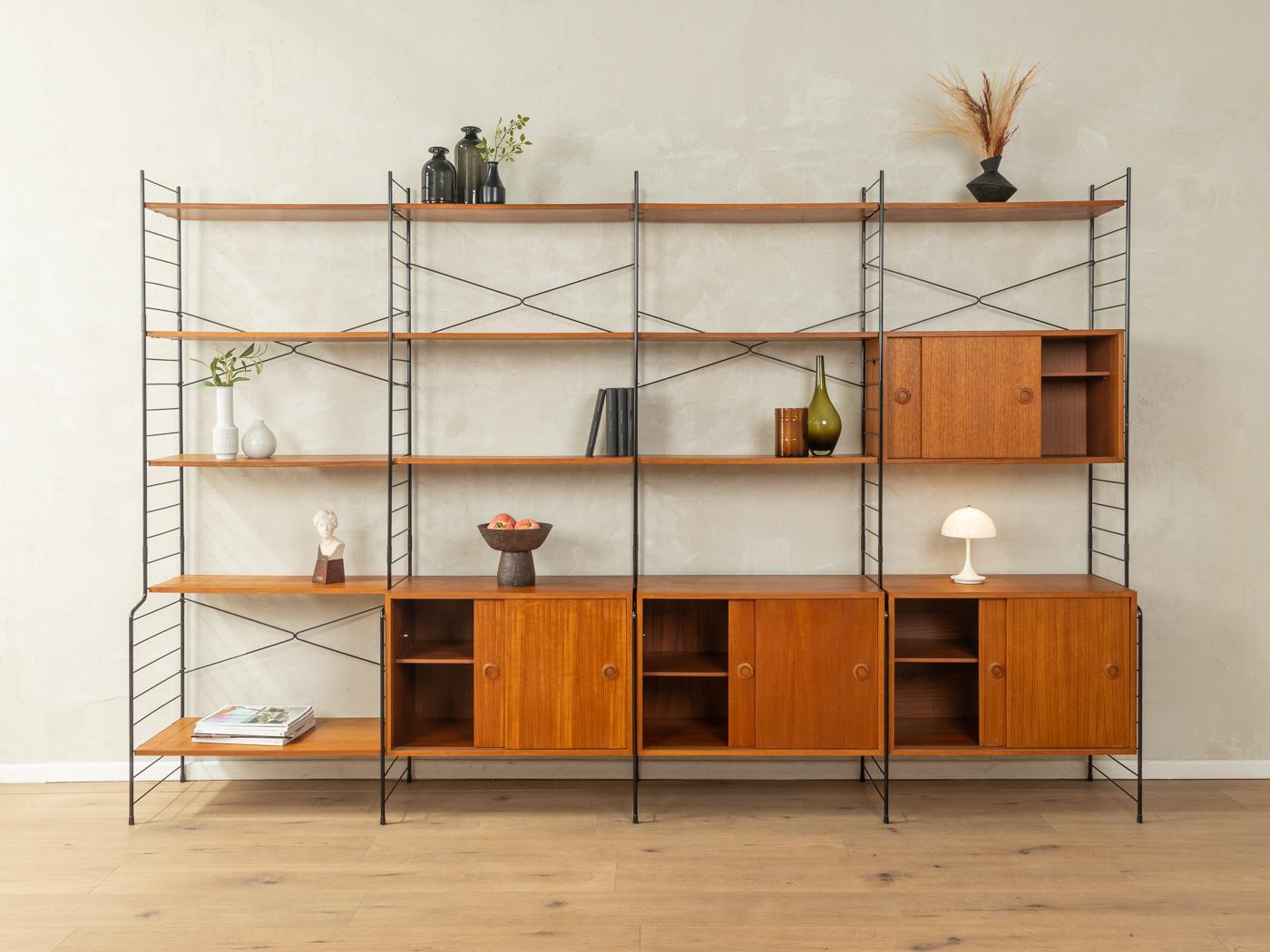 Wunderschönes Regalsystem aus Teakholzfurnier aus den 1960er Jahren. Das System besteht aus fünf schwarzen Metallleitern, vier Containern mit Schiebetüren und einem Regal sowie zwölf Einlegeböden.

Qualitätsmerkmale:
Hochwertige MATERIALIEN
sehr