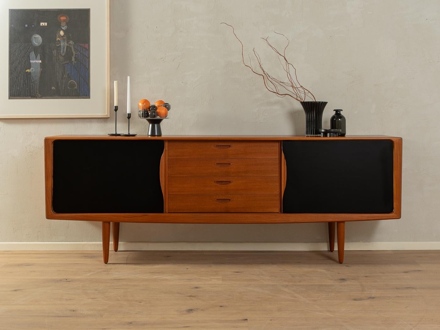 Classic sideboard from the 1960s by H.W. Klein for Bramin. High quality corpus in teak veneer with four drawers, sliding doors, two shelves and solid wood feet. The sliding doors are coated with black Formica.

Quality Features:
    accomplished