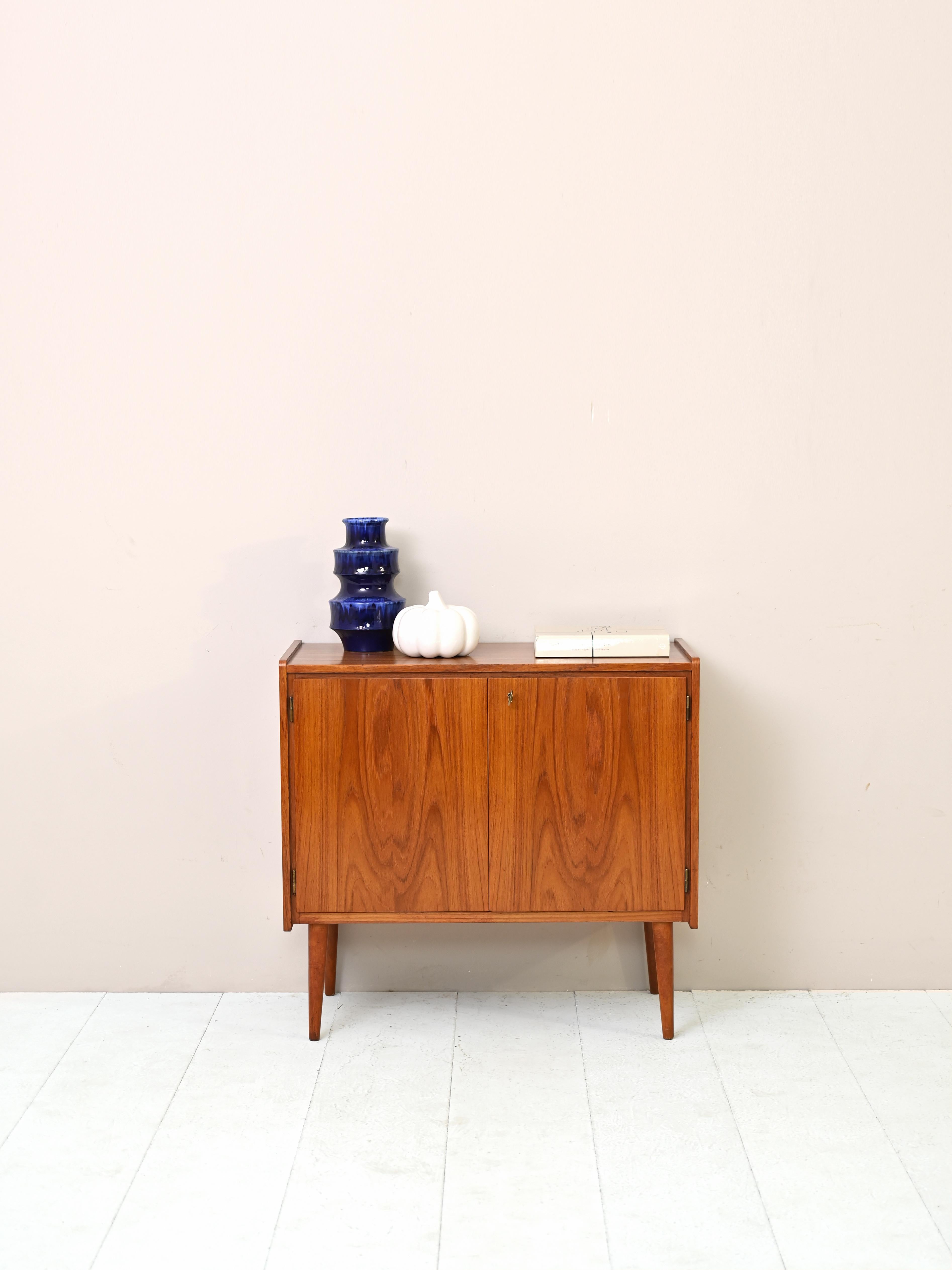 Small Scandinavian teak sideboard with hinged doors.
The simple teak frame features two lockable hinged doors inside which is
is a compartment equipped with a shelf.
A piece of furniture with retro charm that thanks to its small size can be used