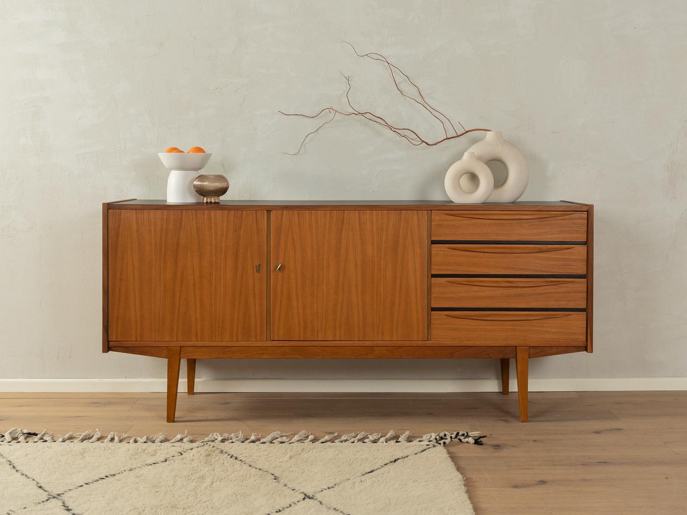 Magnifique buffet des années 1960. Corpus en placage de noyer avec deux portes de placard, quatre tiroirs, une étagère et des pieds droits. Le plateau est revêtu de Formica noir.

Caractéristiques de qualité :

    très bon travail
    des matériaux
