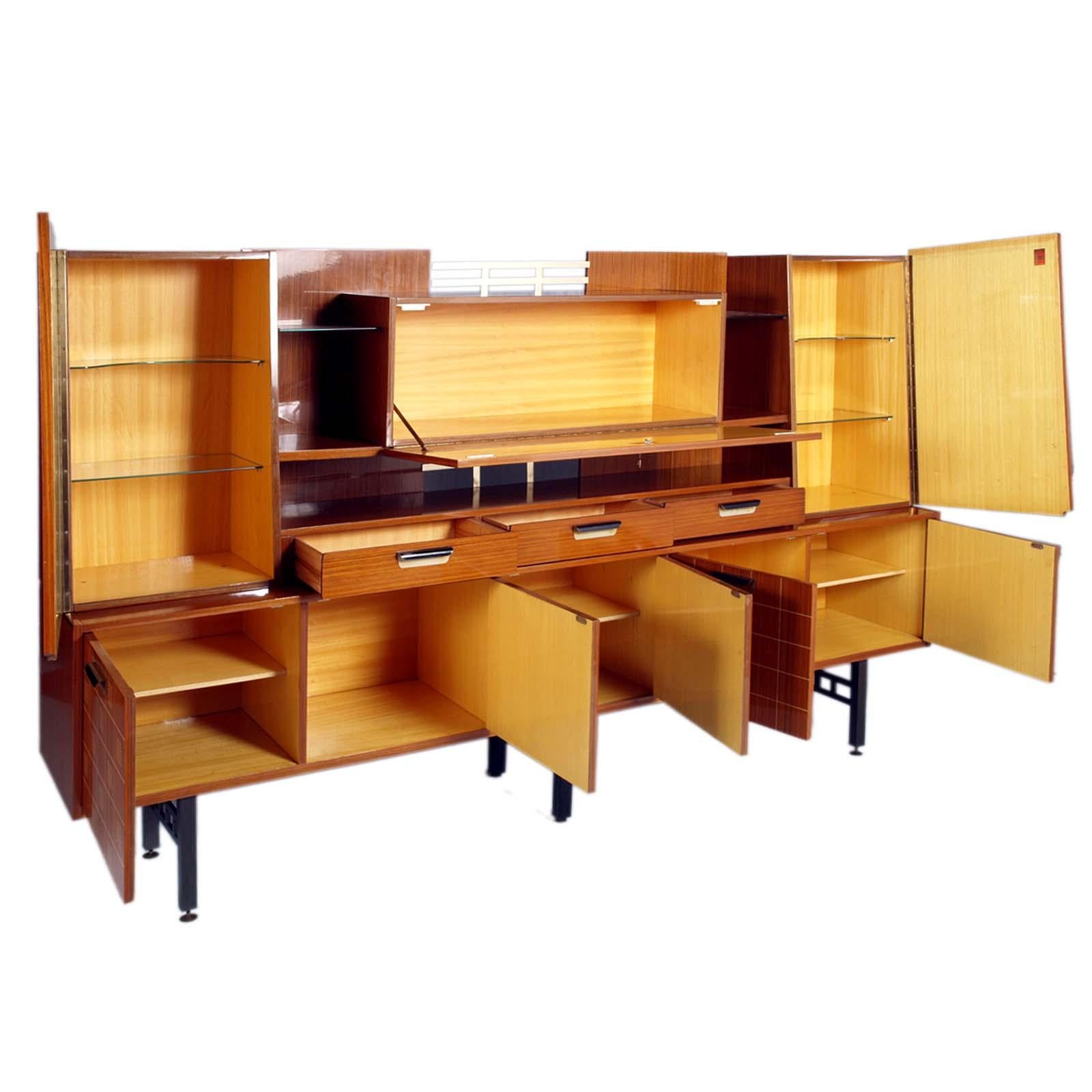 Grande credenza caratteristica del Mid Century Modern di design italiano di La Permanente Mobili Cantu con ribalta centrale, impiallacciata in palissandro, ripiani in vetro, con decorazioni a intarsio sulle ante e gambe in metallo. Interni