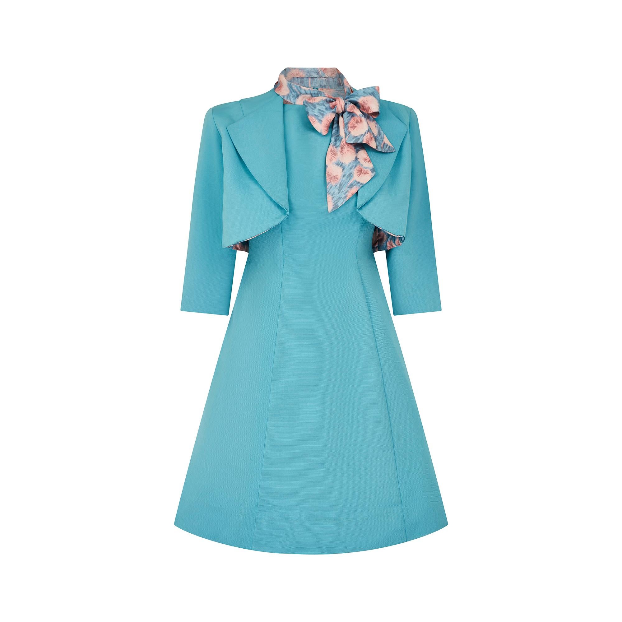 Crafted from silk faille fabric in vibrant aqua blue, this two-piece dress suit was couture made in France during the 1960s. The jacket is cut in a cropped bolero style, with a wide collar and waterfall tailoring.  The three-quarter length sleeves