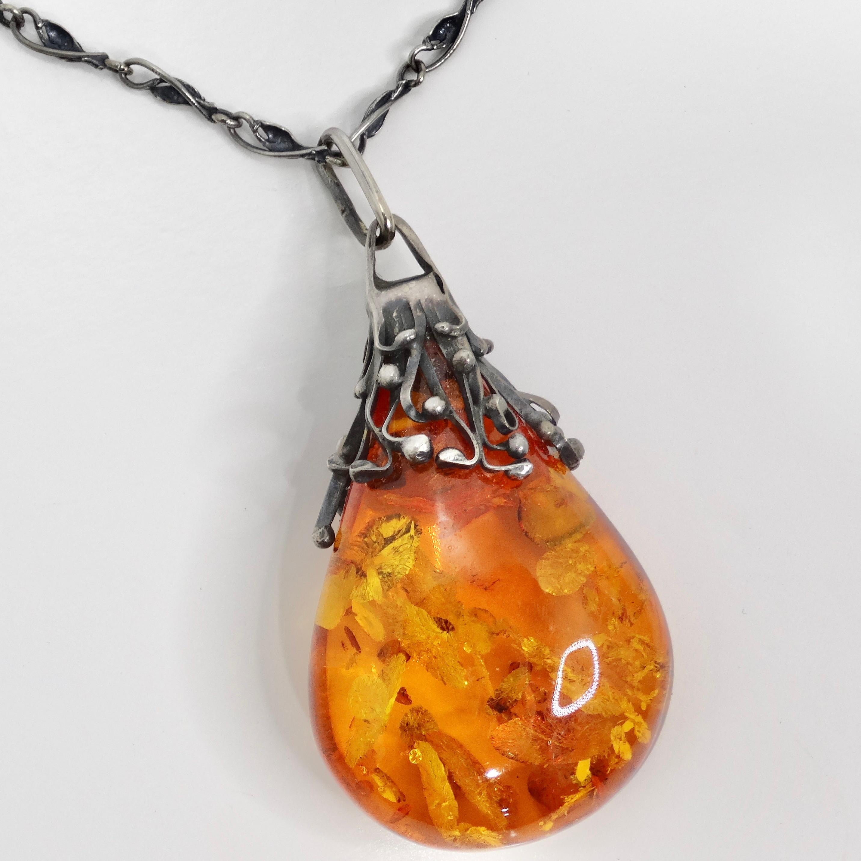 Introducing the 1960s Silver Amber Pendant Necklace, a captivating vintage piece that exudes luxury and elegance. This beautiful necklace features a vintage silver chain that supports a large statement amber stone, creating a stunning focal point