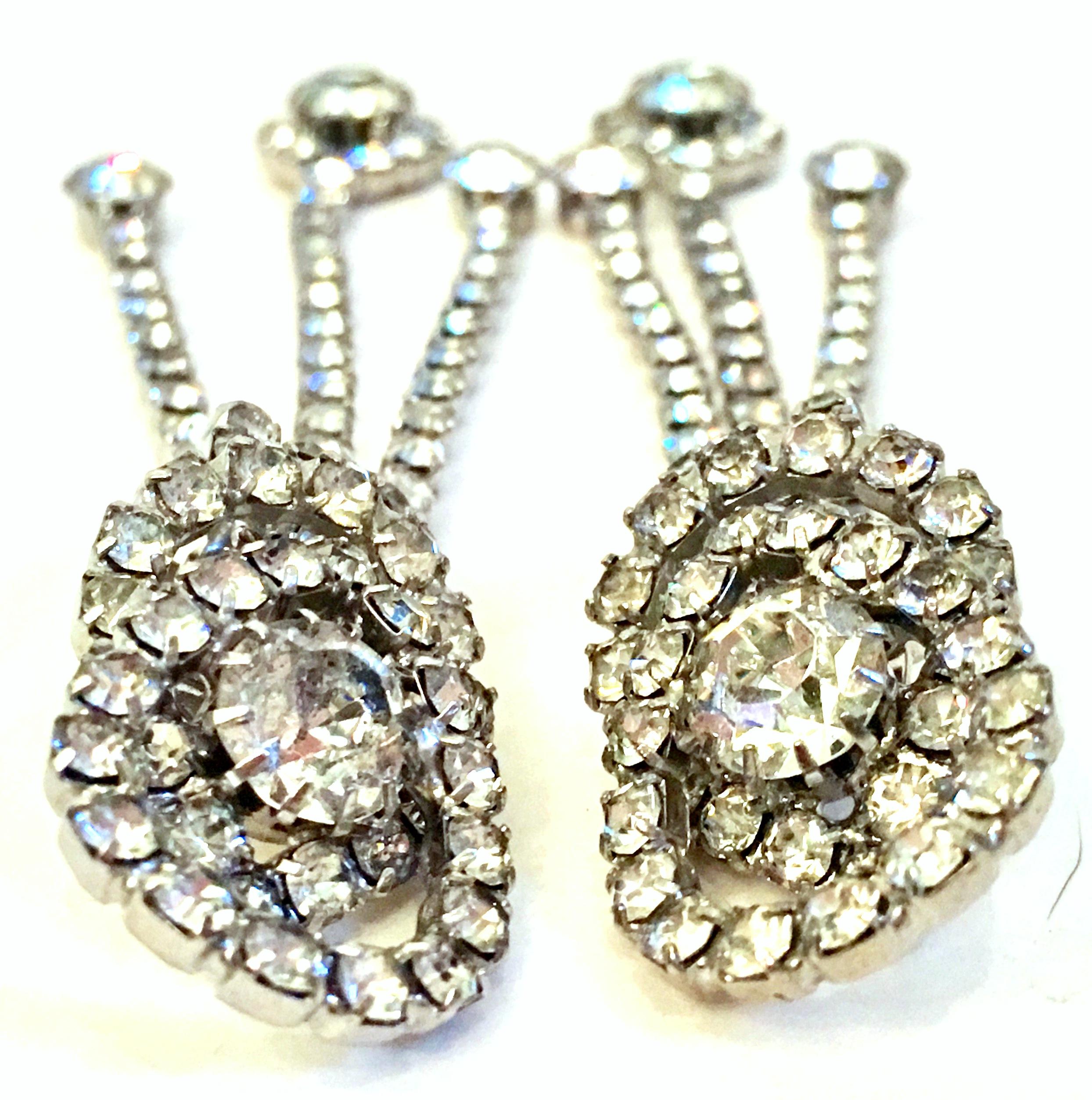 1960's  Silver & Austrian Crystal Dimensional Dangle Earrings. These long clip style earrings feature brilliant cut and faceted prong set colorless stones set in silver rhodium plate.