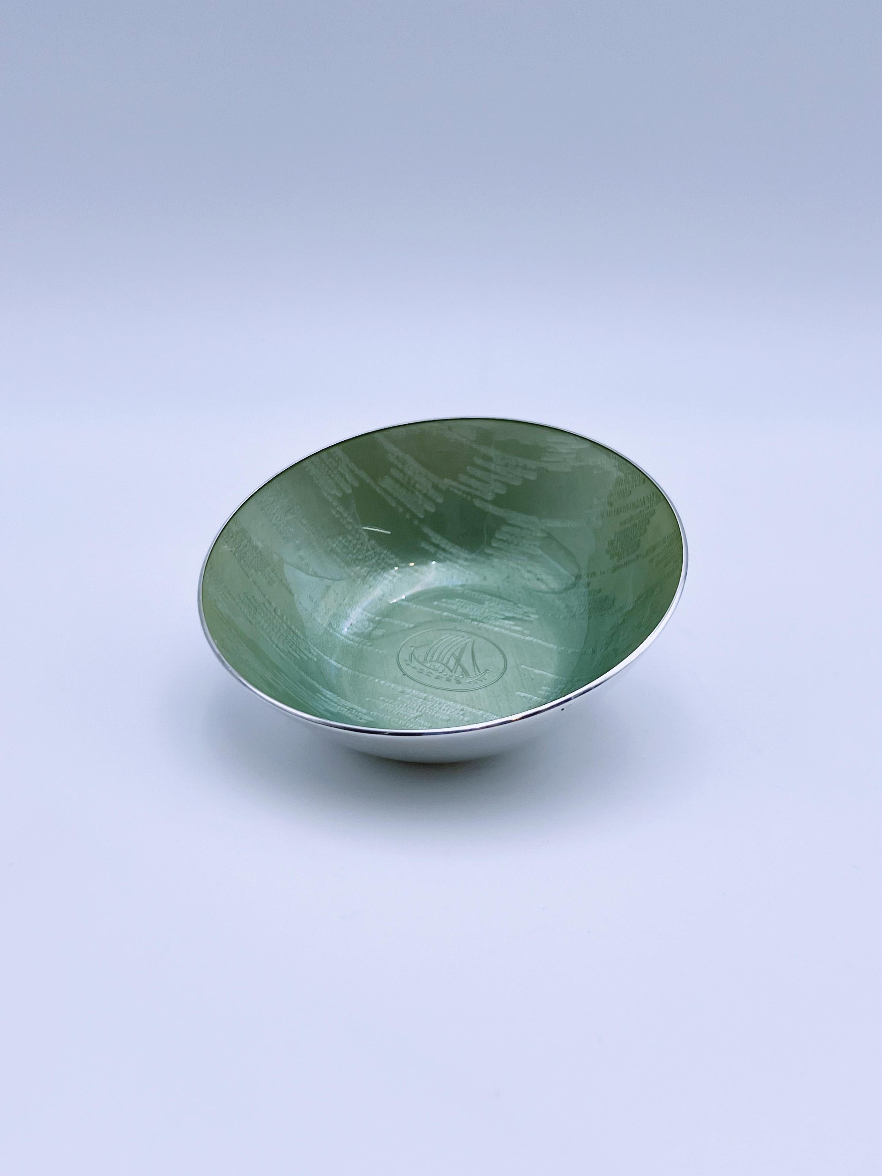 Ciotola in argento e smalto norvegese del 1960 di Grete Prytz Kittelsen per J. Tostrup

Questa ciotola moderna di metà secolo presenta un sorprendente motivo a nave vichinga su uno smalto a specchio verde chiaro. Disegnato dalla famosa Grete Prytz