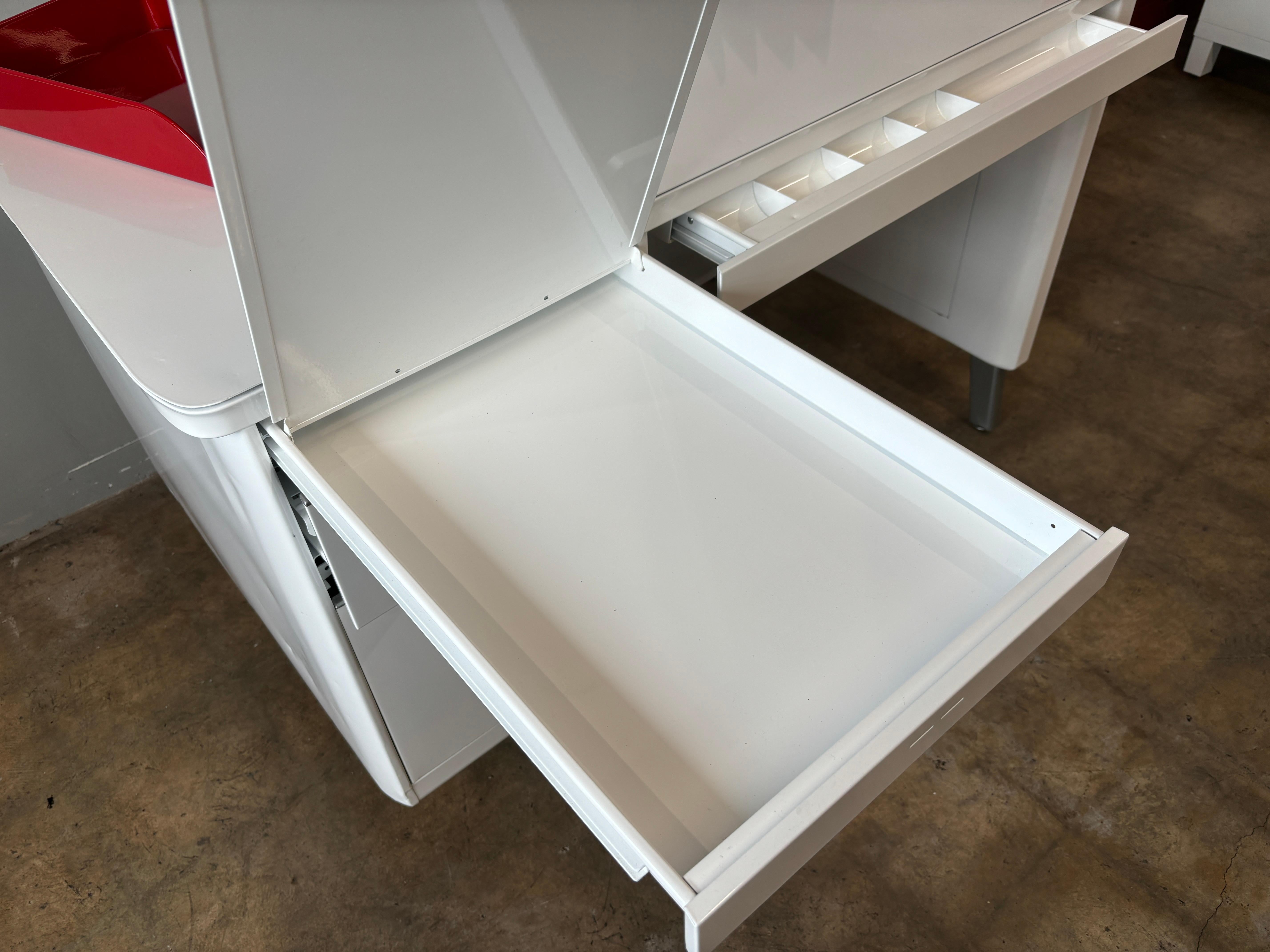 1960s Steel single pedestal tanker desk refinished in gloss white powder coat finish. 
Metallic silver hardware.  File, box and middle pencil drawer and unique pull out writing / storage tray.   

49” x 30” x 29” h.   

Great for students or