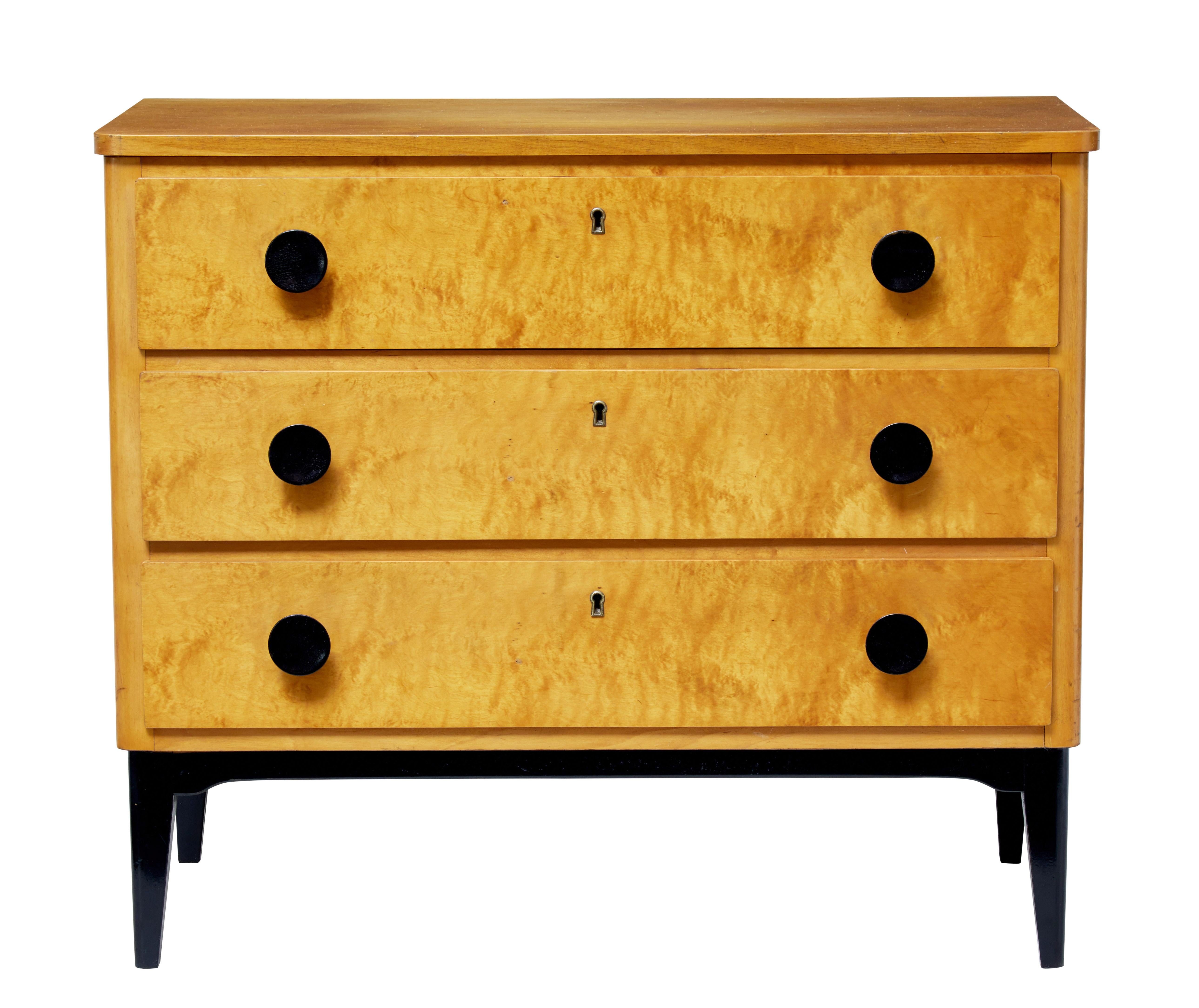 Good quality petit chest of drawers, circa 1960.

Three equal proportioned drawers with round ebonized handles.

Golden birch color, standing on contrasting ebonized legs to match the handles.

Some surface wear and fading to top surface.