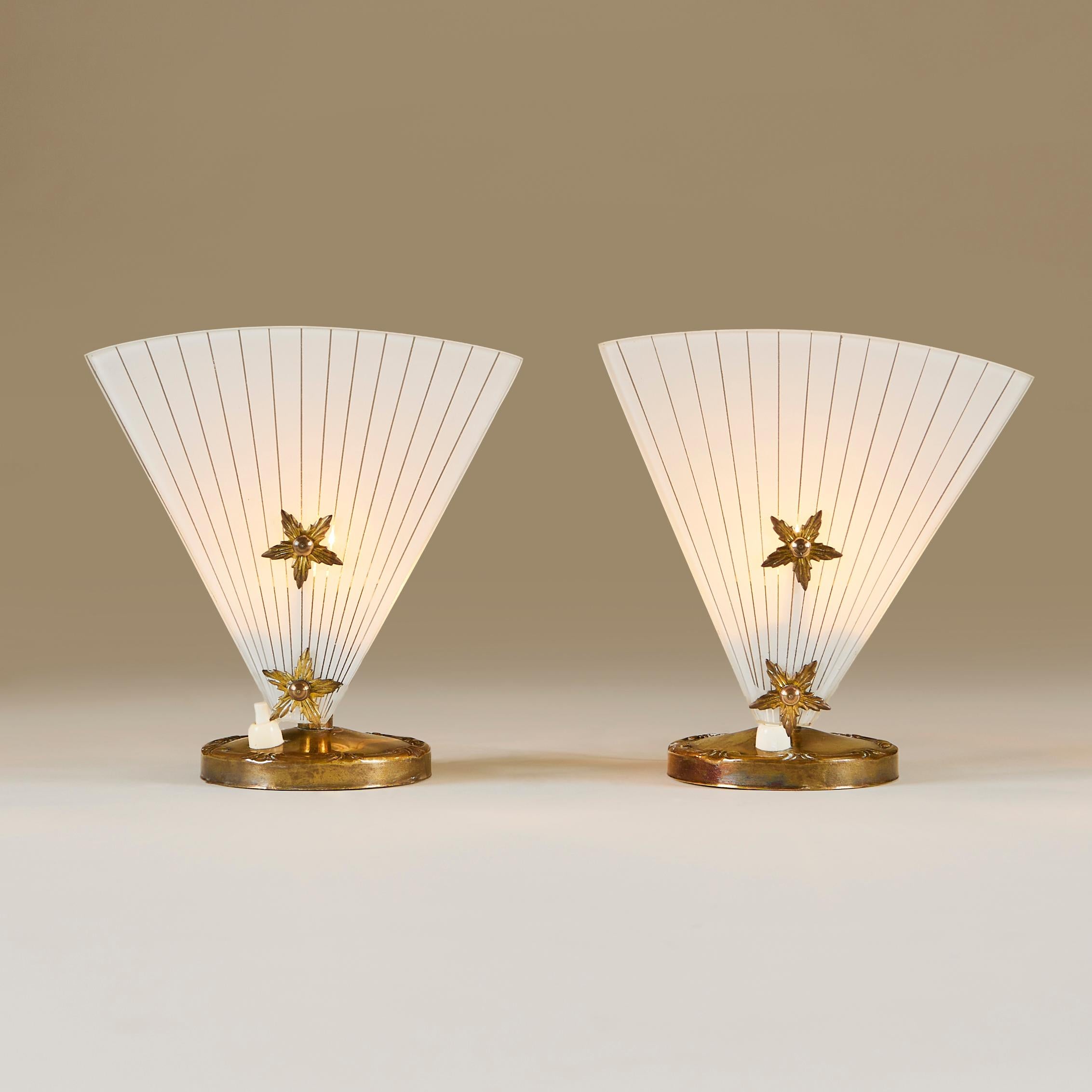 Unusual pair of small dressing-table/table lamps. Decorative brass fitting in the shape of a chamber stick with a striped fan shaped glass panel each secured with two brass stars. Exudes a flattering light.