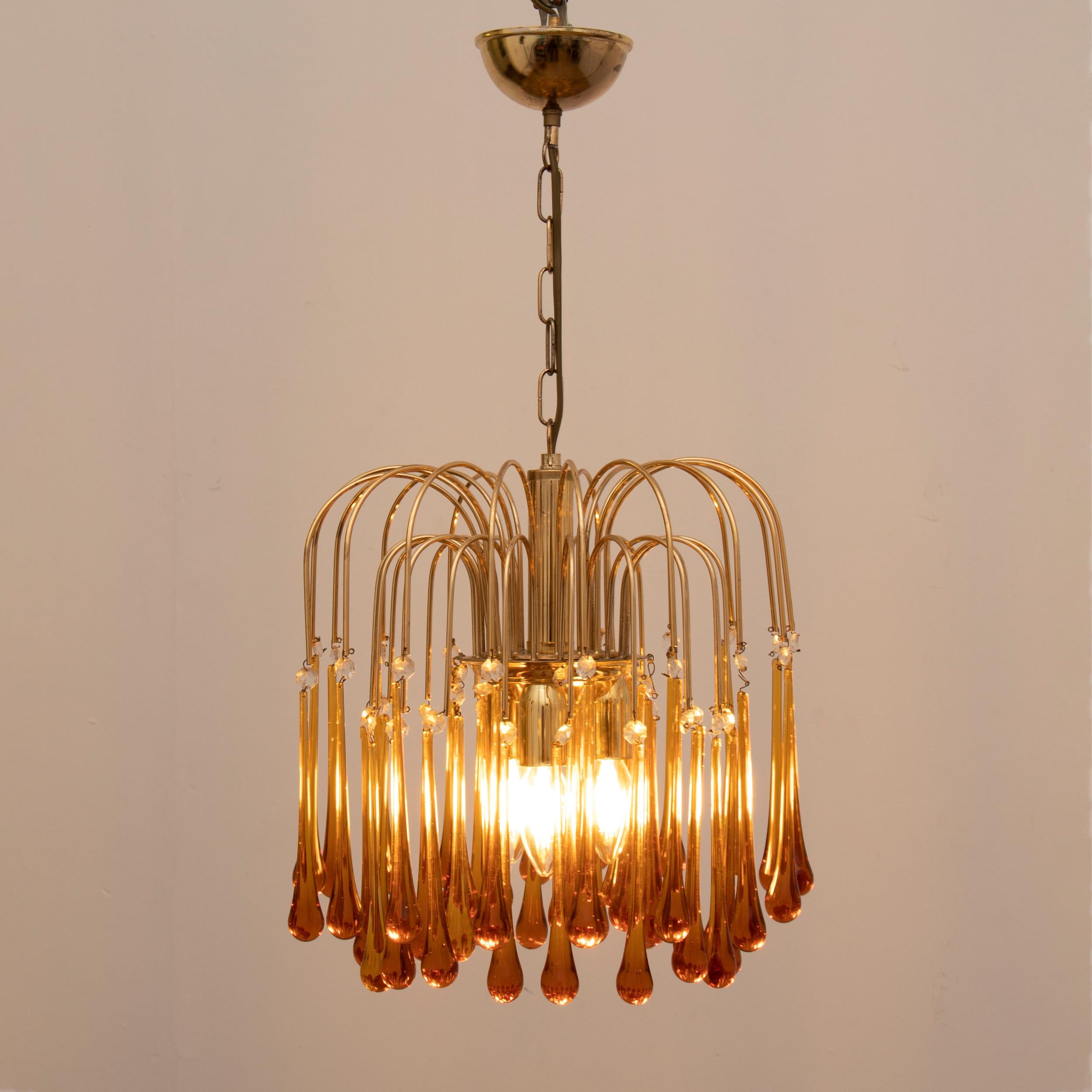 A small 1960s Italian Murano Amber glass, cascading, chandelier designed in the style of by Paolo Venini. There are three-tiers of amber glass teardrops suspended from brass stems with clear glass beads in between them. Three E14 screw in bulbs are