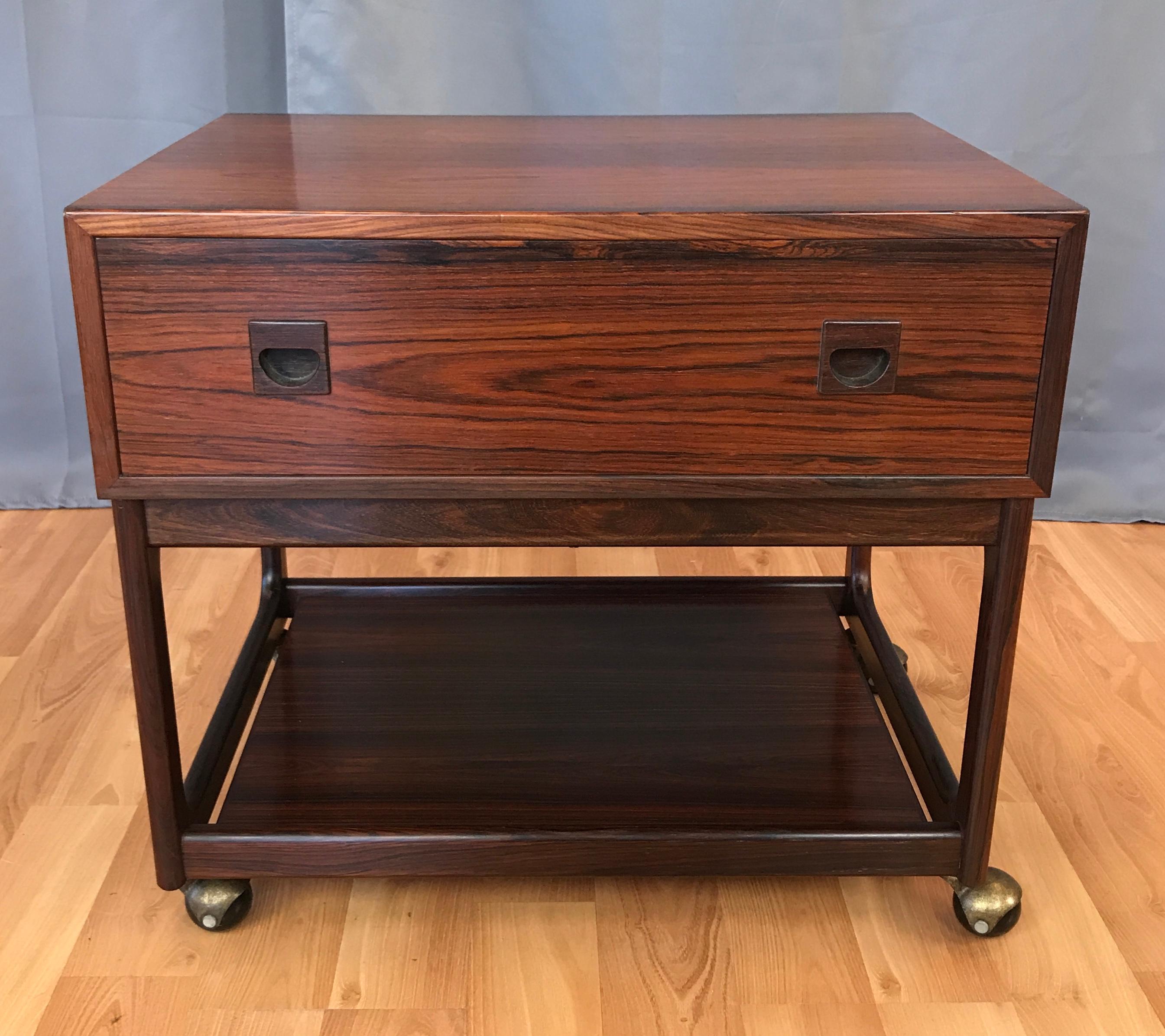 1960s Small Scandinavian Modern Rosewood work cabinet or table on wheels.
A great looking small Danish design rosewood chest with a drawer, inside of the drawer there a sliding wooden tray. Screws are brass, bottom of the unit has a Rosewood shelf,