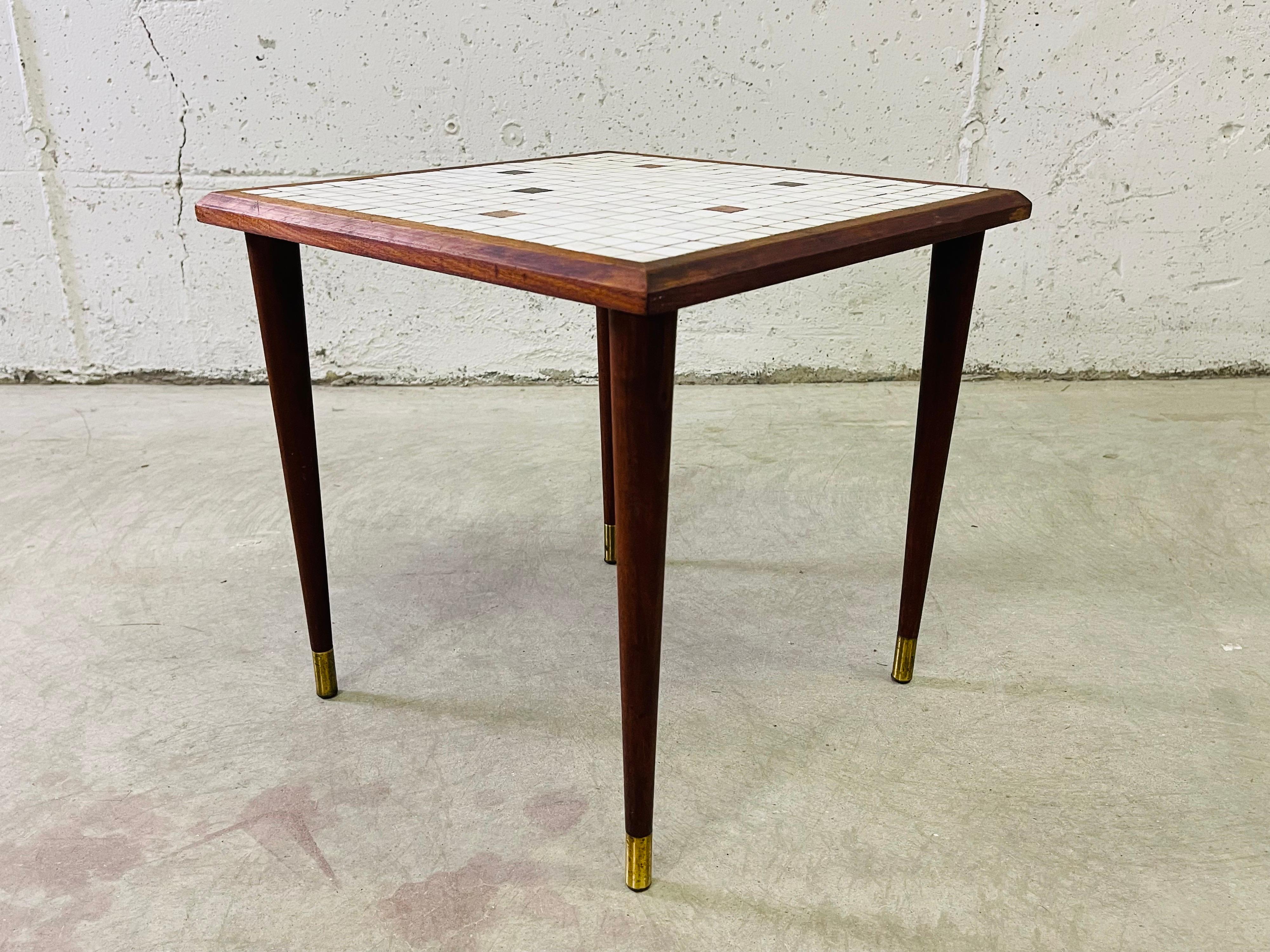 Vintage 1960s small square tile top table side table with round legs. The tile is white with gold accented tiles. The legs have brass accents. No marks.