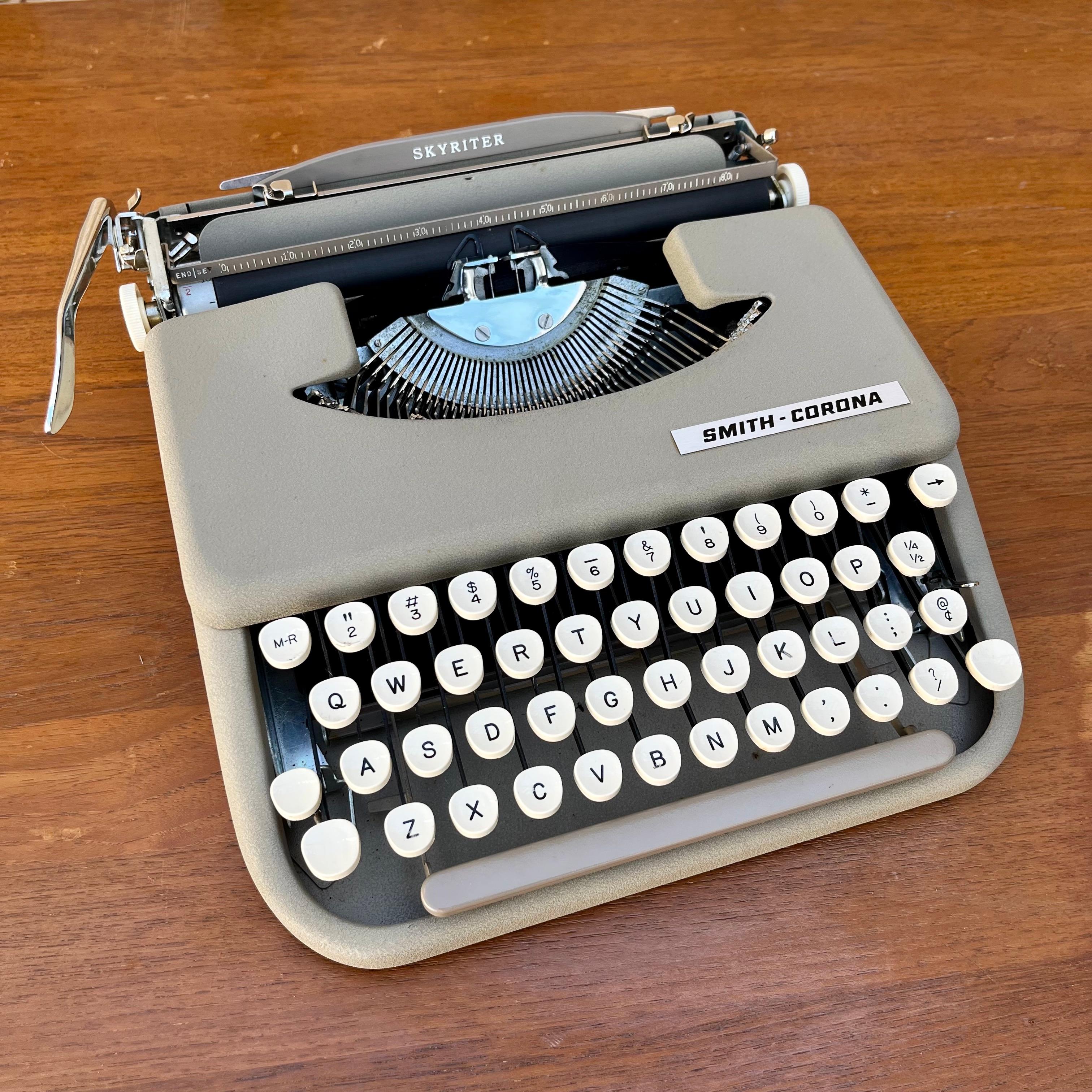 Vintage Mid-Century Modern Smith Corona Skyriter portable typewriter with the original tan vinyl case. Circa 1960s 
Despite its lean lines, lightness, and simplicity the Smith Corona Skyriter Portable Typewriter is a sturdy machine, considered by