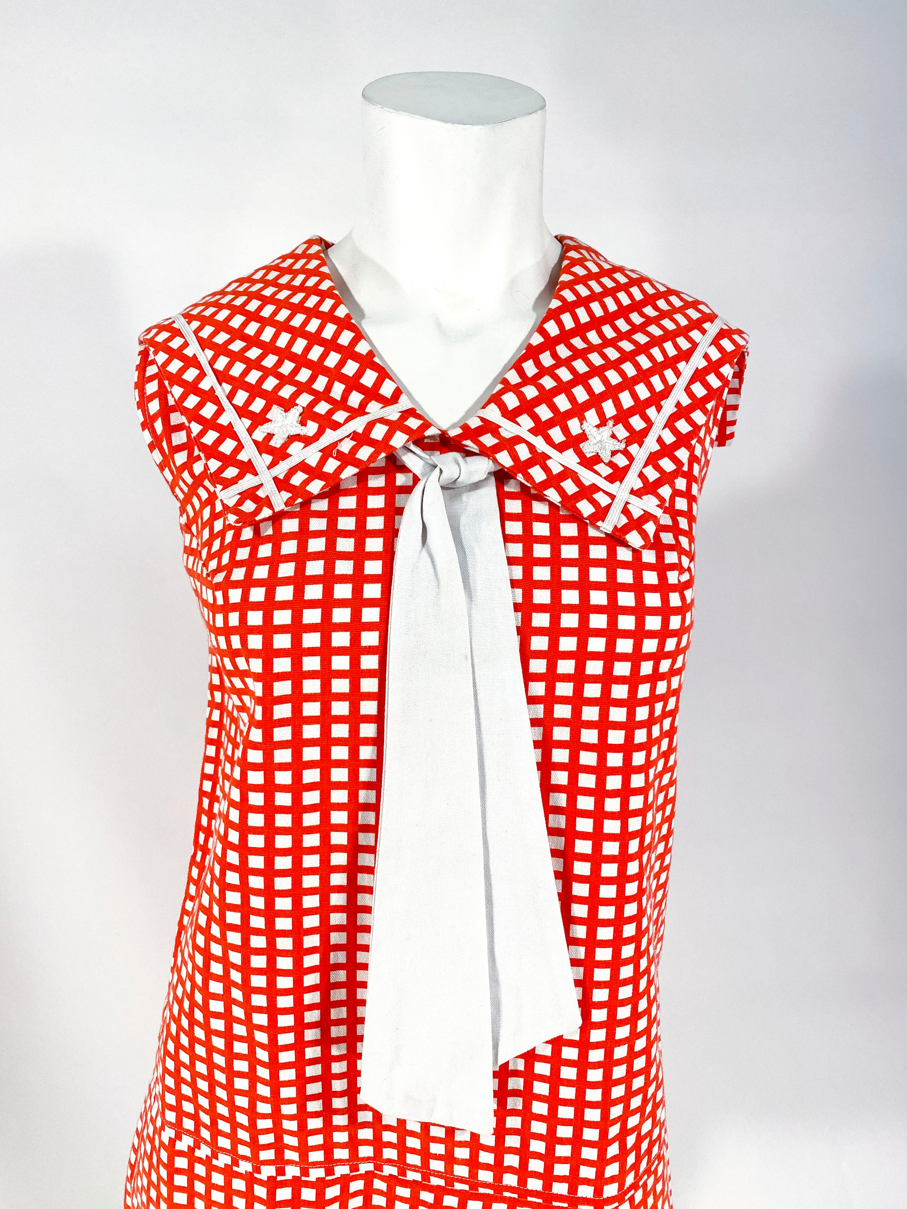 1960s soft red and white printed cotton skort dress with large pleats that hide the shorts of the skort, windowpane pattern, sailor collar decorated with soutache trim and embroidered stars, finished with a white cotton sailor tie. The back has a