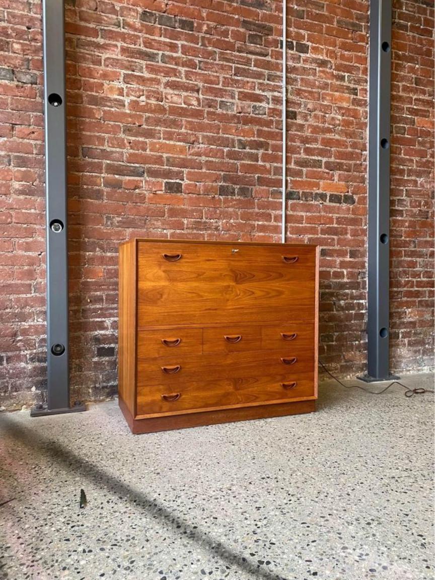 Exquisite and uncommon solid teak bar cabinet, a masterpiece of design by Peter Hvidt for Søborg Møbelfabrik in the 1960s. This remarkable piece boasts a cleverly concealed drop-down mixing surface, while the discreetly lowered section of the main