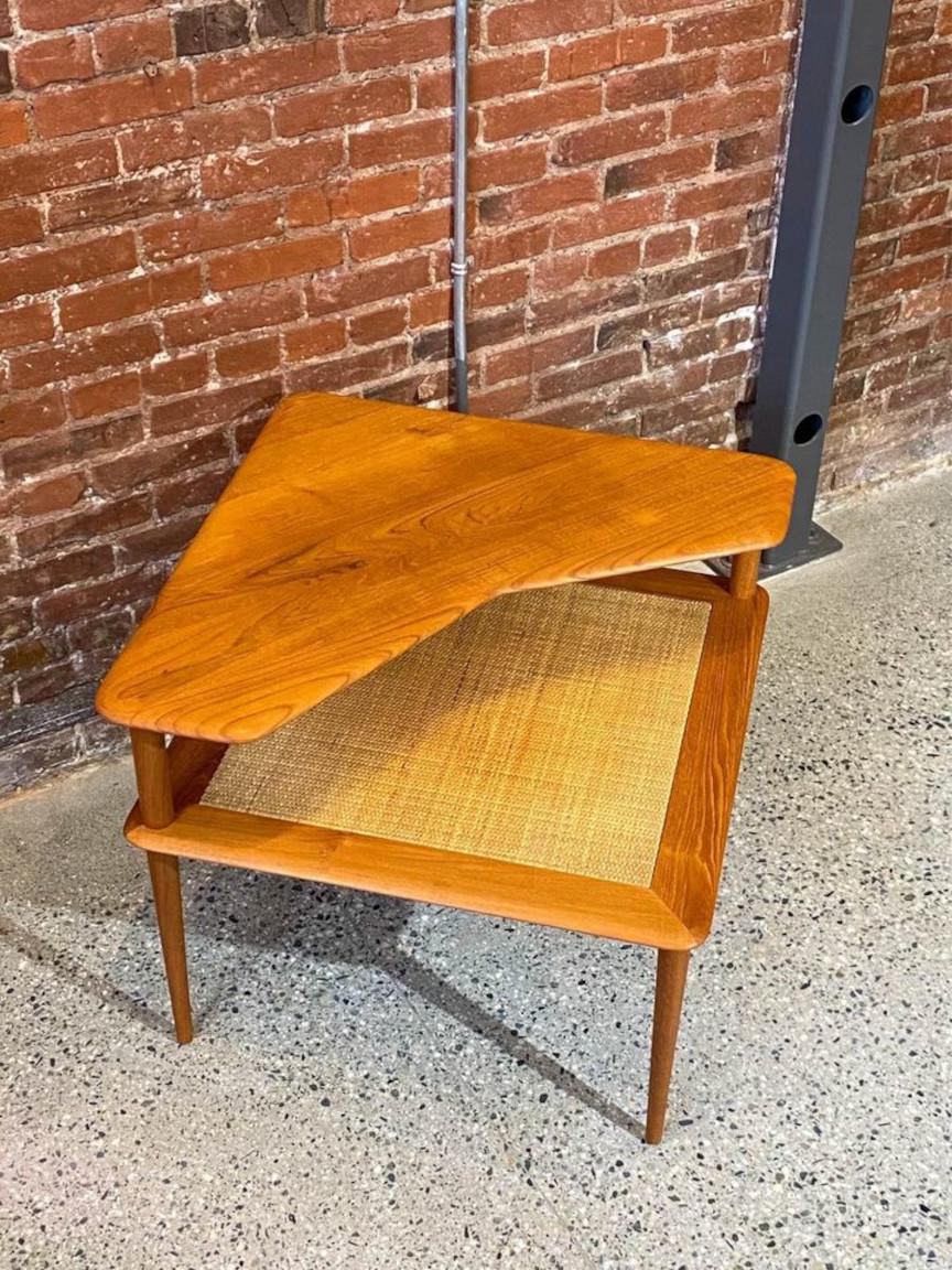 A delightful complement to contemporary interiors, this exquisite corner table, designed by Peter Hvidt for France & Son during the 1960s, boasts a beautifully figured solid teak top and an impeccably fashioned pleated rattan lower surface.