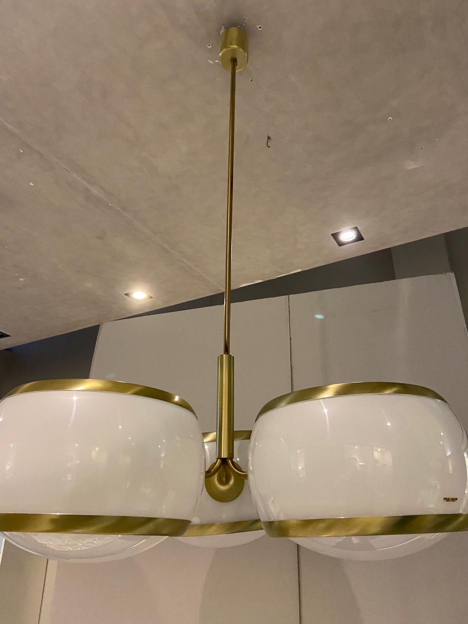 A white acrylic and gilded metal three-lights chandelier designed and manufactured in the sixties by Stilux. The chandelier comes from an important lighting shop that was going out of business, so it has never been installed in a home and,