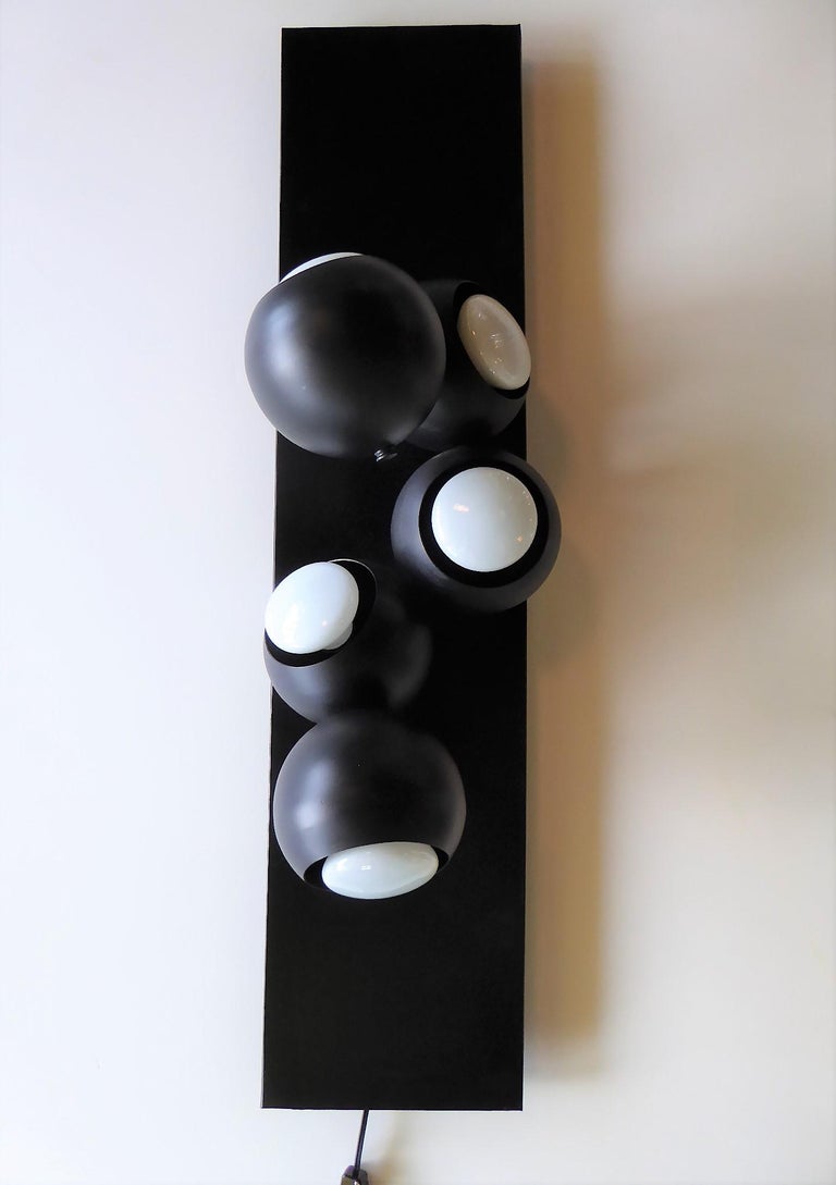 Super Space Age wall light or sconce in the style of Robert Sonneman. In a black color, it is a Molecule or Bubble Light consisting of 5 round ball lights mounted on a black backing. Measurements are without bulbs. The light takes medium (Edison)
