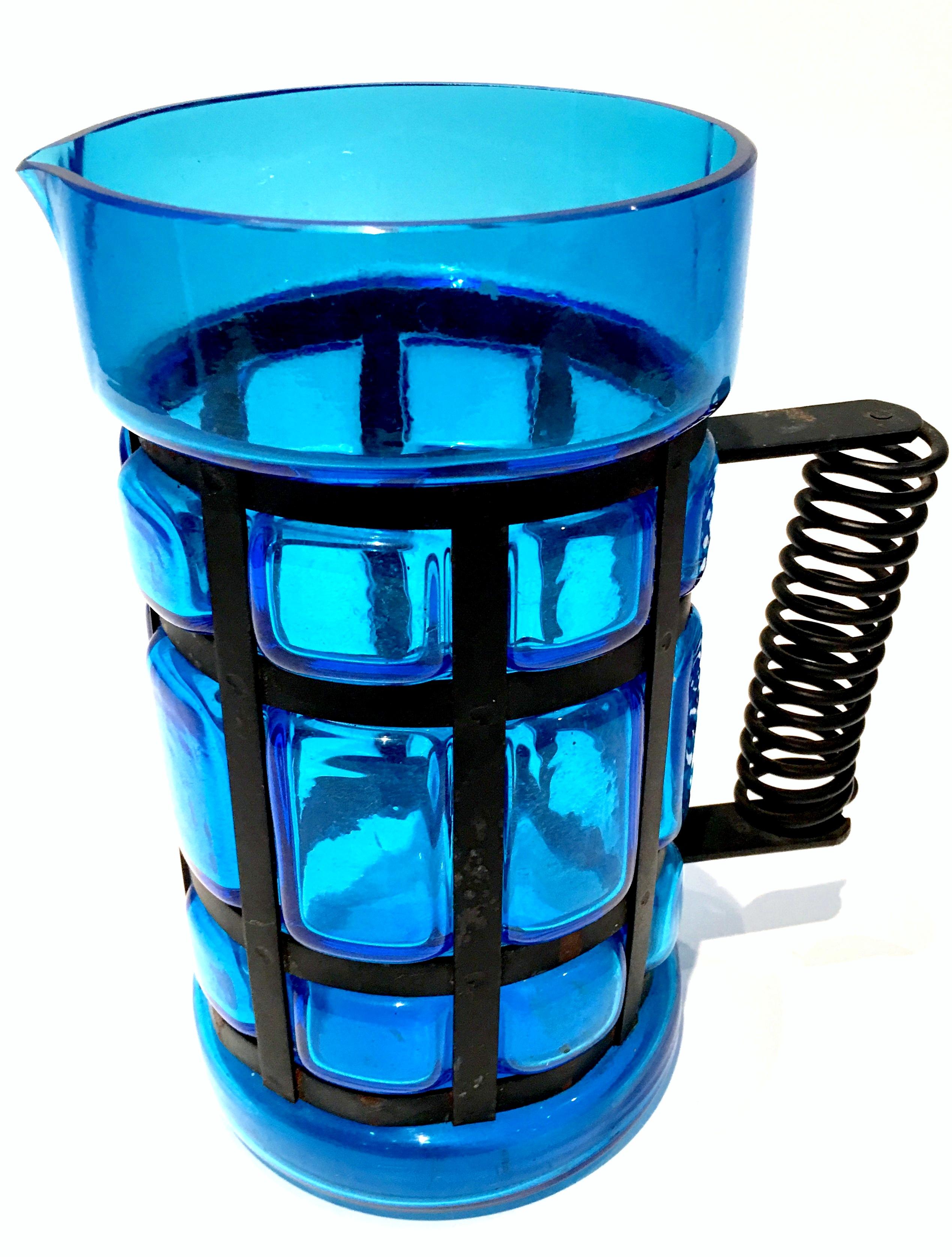 Mid-Century Spanish Peacock Blue blown glass & iron caged handled pitcher. Brilliant blue glass with black cast iron. The handle has a spiral detail and the body is pillowed. Measure: Handle, 5