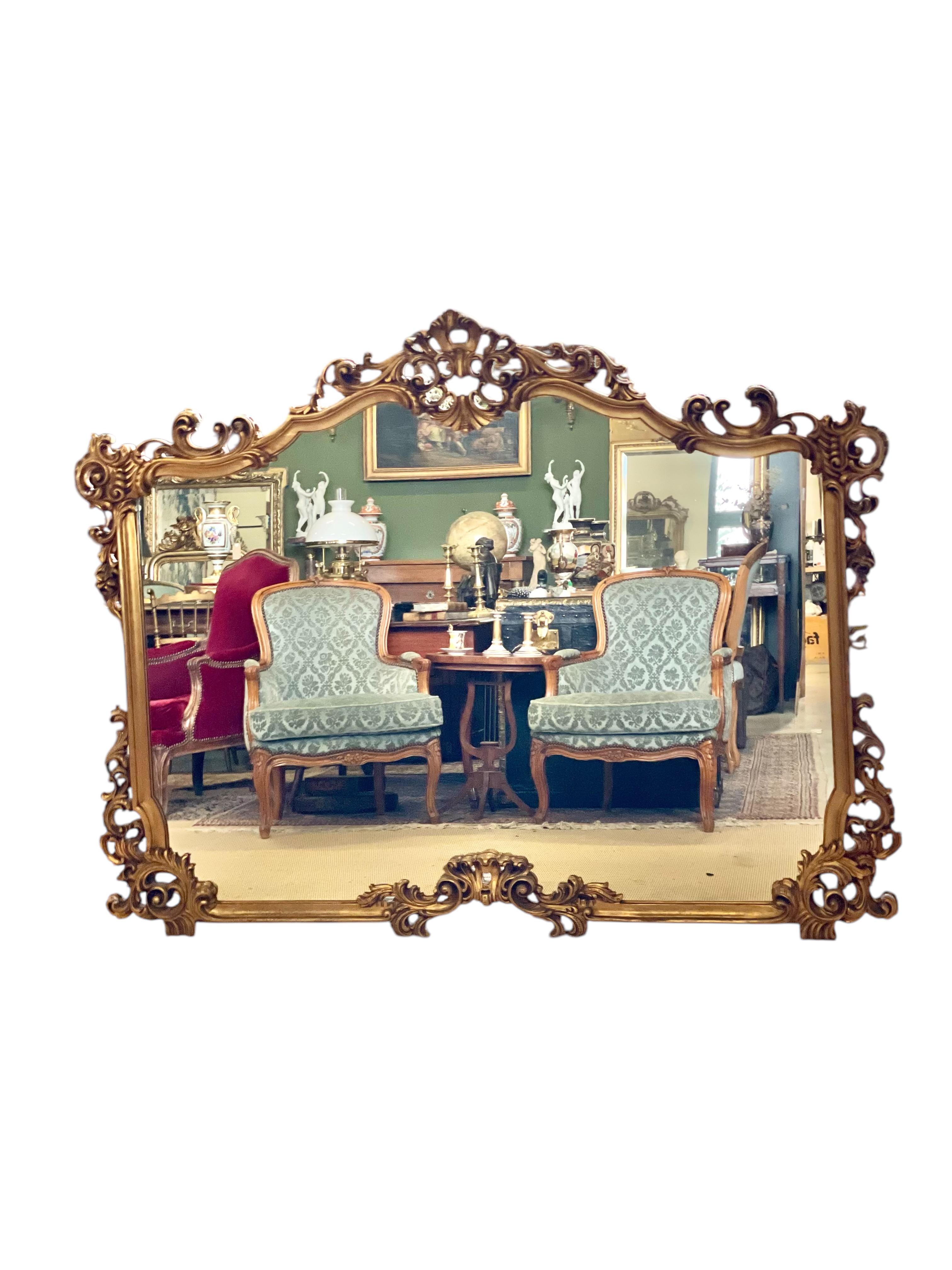 Ce magnifique miroir rectangulaire est un véritable coup de cœur. Datant des années 1960, il respire la grandeur de l'époque rococo avec son cadre en bois doré et sculpté de manière complexe. Le fronton ajouré spectaculaire est orné d'une grande