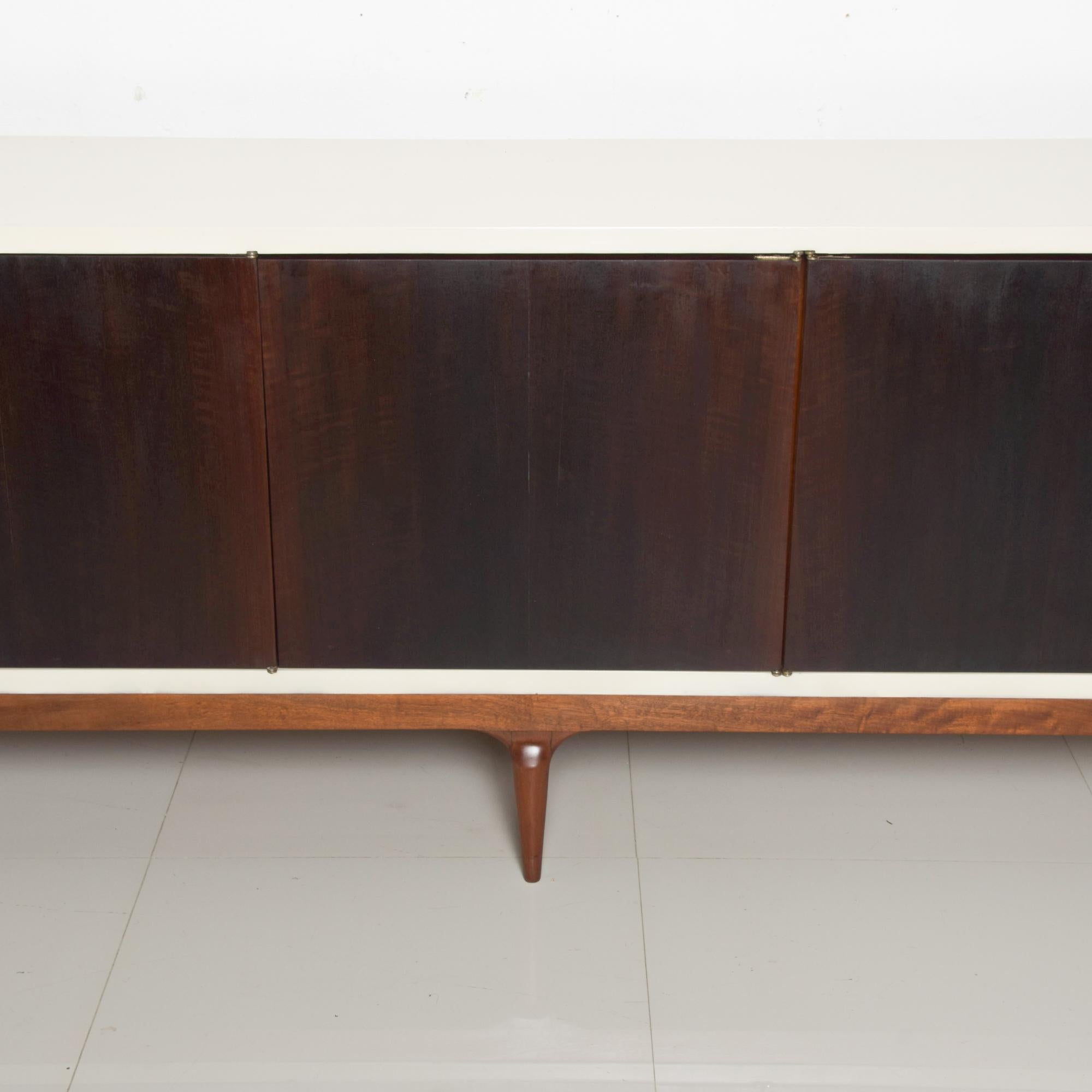 Spectacularly sleek clean modern line credenza made in Monterrey, Mexico, circa early 1960s.
Lean long leggy credenza two tone lacquer & wood
Restored by Ambianic with lacquered top in an off-white with gold leaf accent.
Five doors finished with