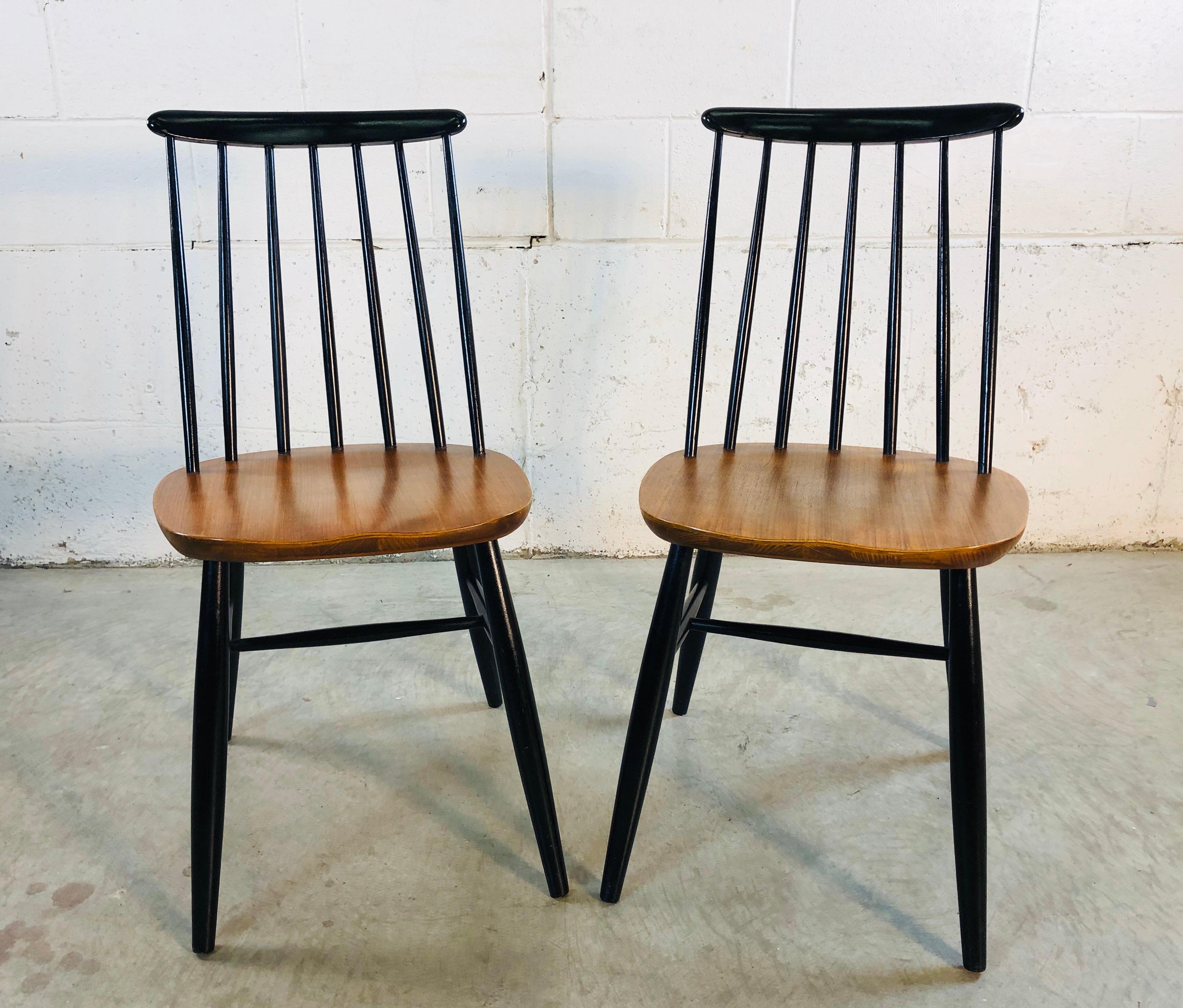 Vintage 1960s pair of spindle back teak and black painted dining chairs. The chairs are in refinished condition and are solid and sturdy. Marked Yugoslavia underneath. Measures: Seat 17.5” H.