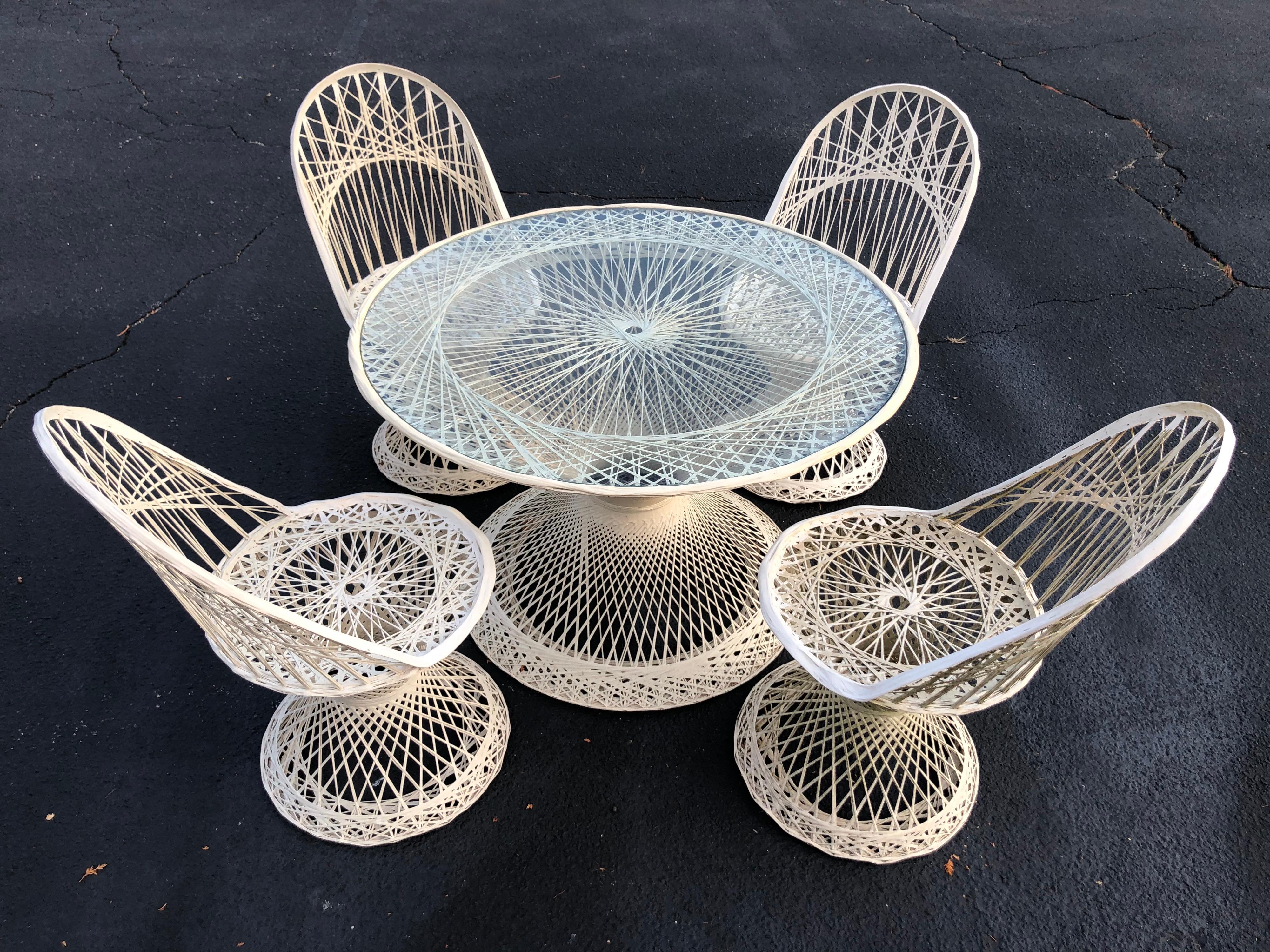 Mid Century spun fiberglass patio set by Russell Woodard. Fun, atomic age set for that trendy patio.Use in or outdoors. Glass table top that sits recessed above its sculptural base. This set is an off-white cream color. Chairs could use round seat