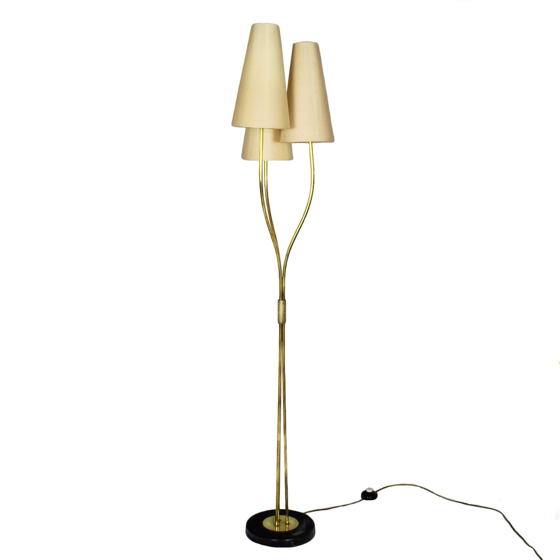 Standing lamp with a round black steel base and three brass-plated steel stands jointed by a brass decoration. Original laminated paper lampshades.

France, circa 1960.