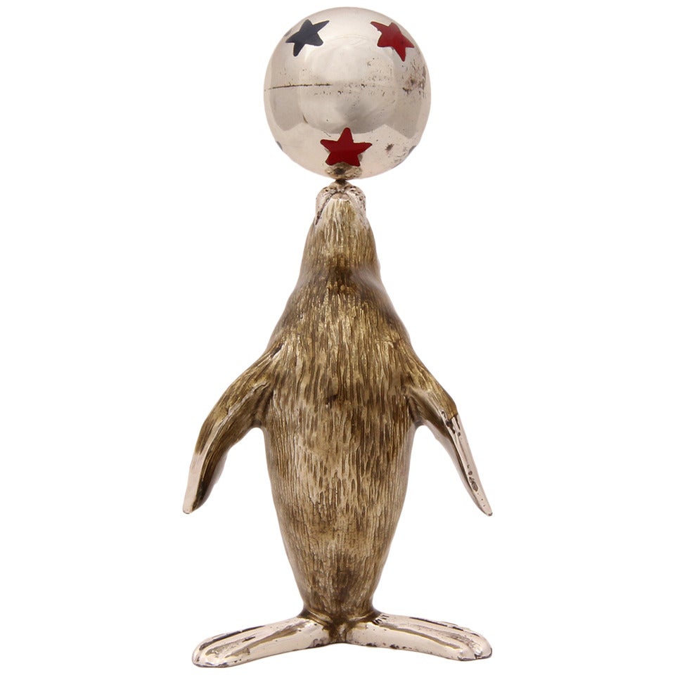 A beautifully modeled and delightful enameled sterling silver figurine of a sea lion balancing a polychromed ball with red and blue stars. Minor enamel loss on the stars.