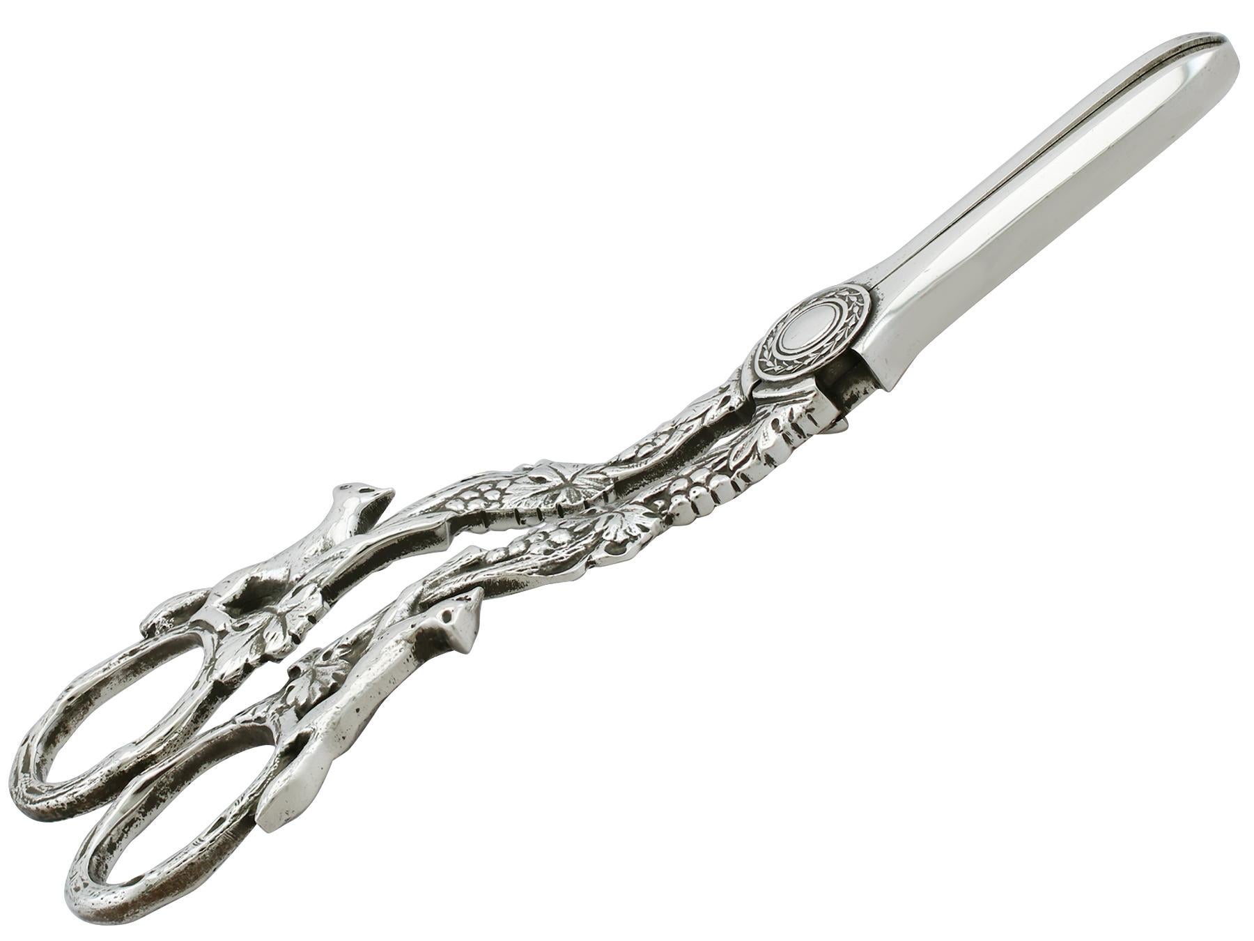 An exceptional, fine and impressive pair of vitnage Elizabeth II English sterling silver grape shears; an addition to our silver flatware collection.

This exceptional pair of vintage silver grape shears, in sterling standard, has a hinged scissor