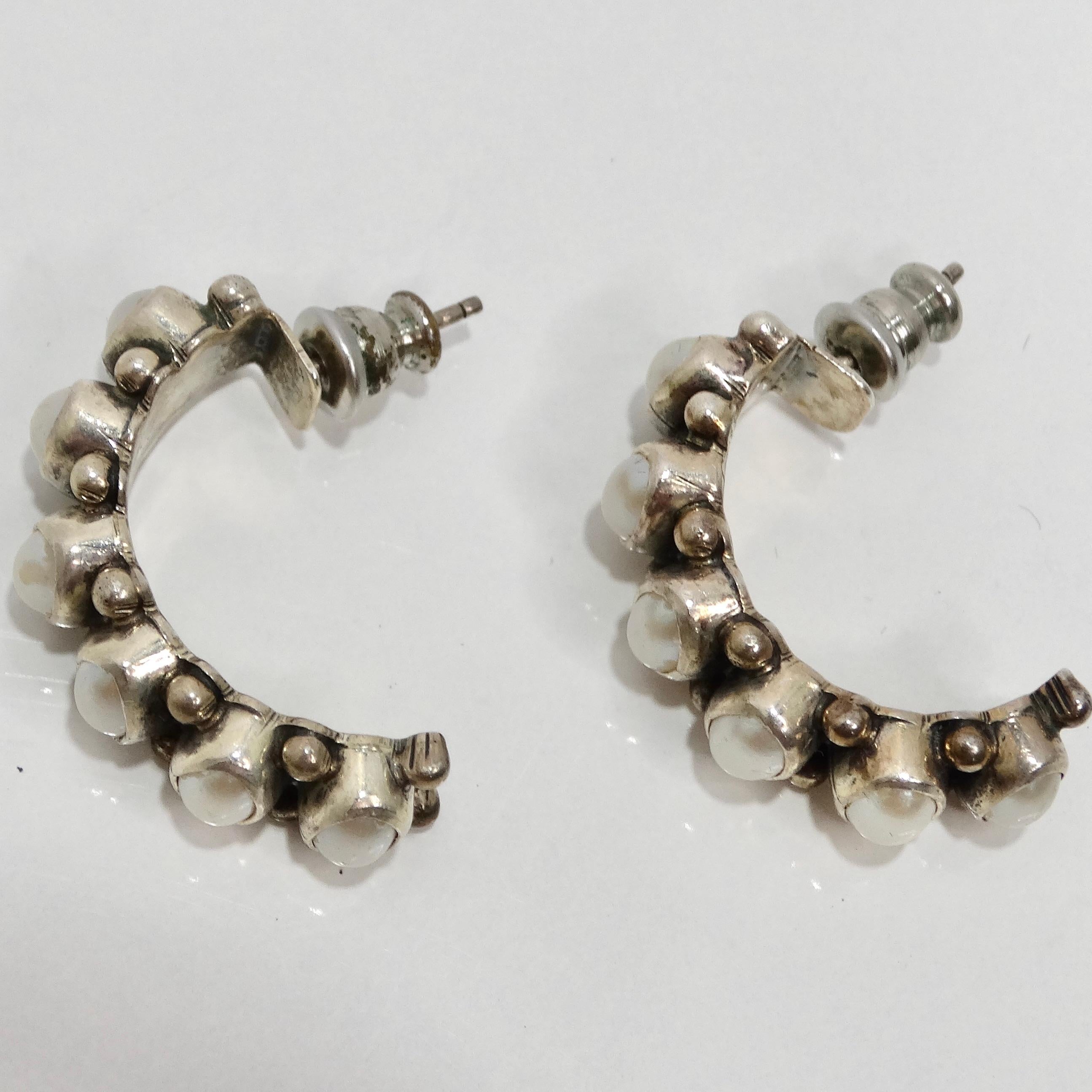 Elevate your style with the 1960s Sterling Silver Pearl Hoop Earrings, a classic pair of crescent-shaped half hoop earrings that beautifully combine authentic oval pearls with luxurious sterling silver. These earrings epitomize classic elegance. The