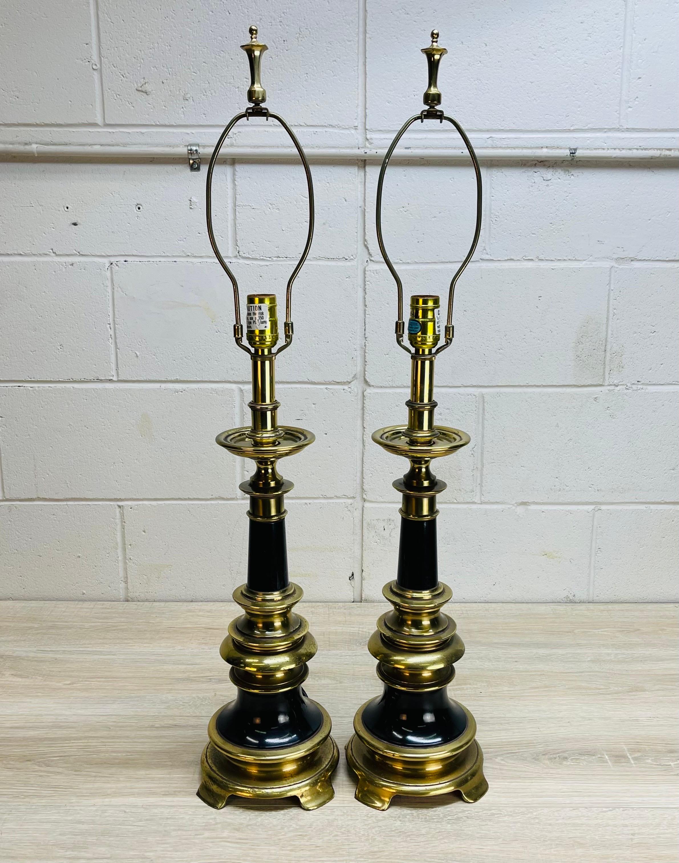 Vintage 1960s pair of Stiffel brass and black metal table lamps. The lamps have the original finials and can use a 3-way 150W bulb. Wired for the US and in working condition. Measures: Socket, 23” H. Harp, 4.5” diameter x 9” height. Marked.