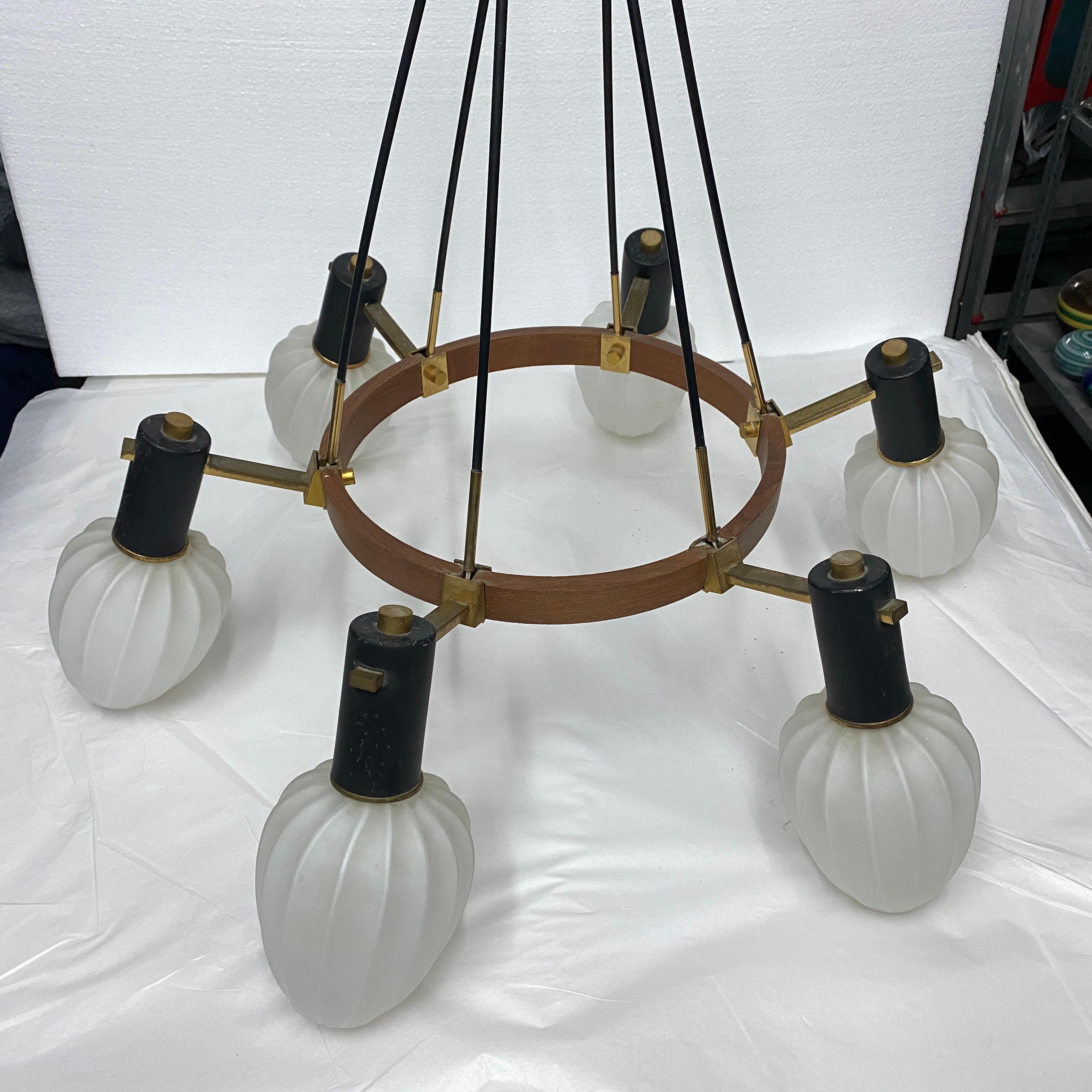 An elegant chandelier designed and manufactured in Italy in the Sixties in the manner of stilnovo. the round teak structure holds six brass and white opaline glass diffusors, it needs 6 regular e14 bulbs and works both 110-240 volts. It's in very
